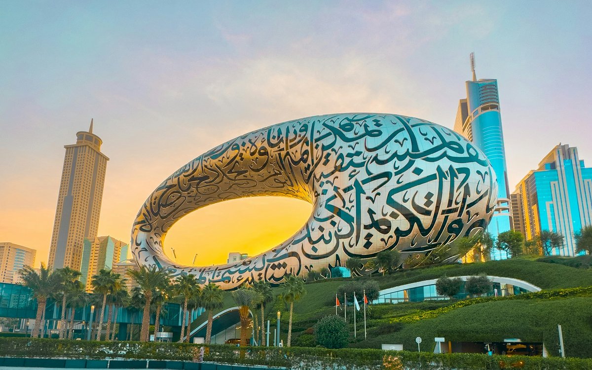 The calligraphy-clad steel ring of the Museum of the Future glows in golden evening light above its landscaped hill in Dubai.