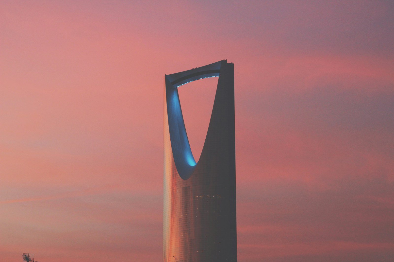 The Kingdom Centre tower against a rose and amber evening sky in Riyadh