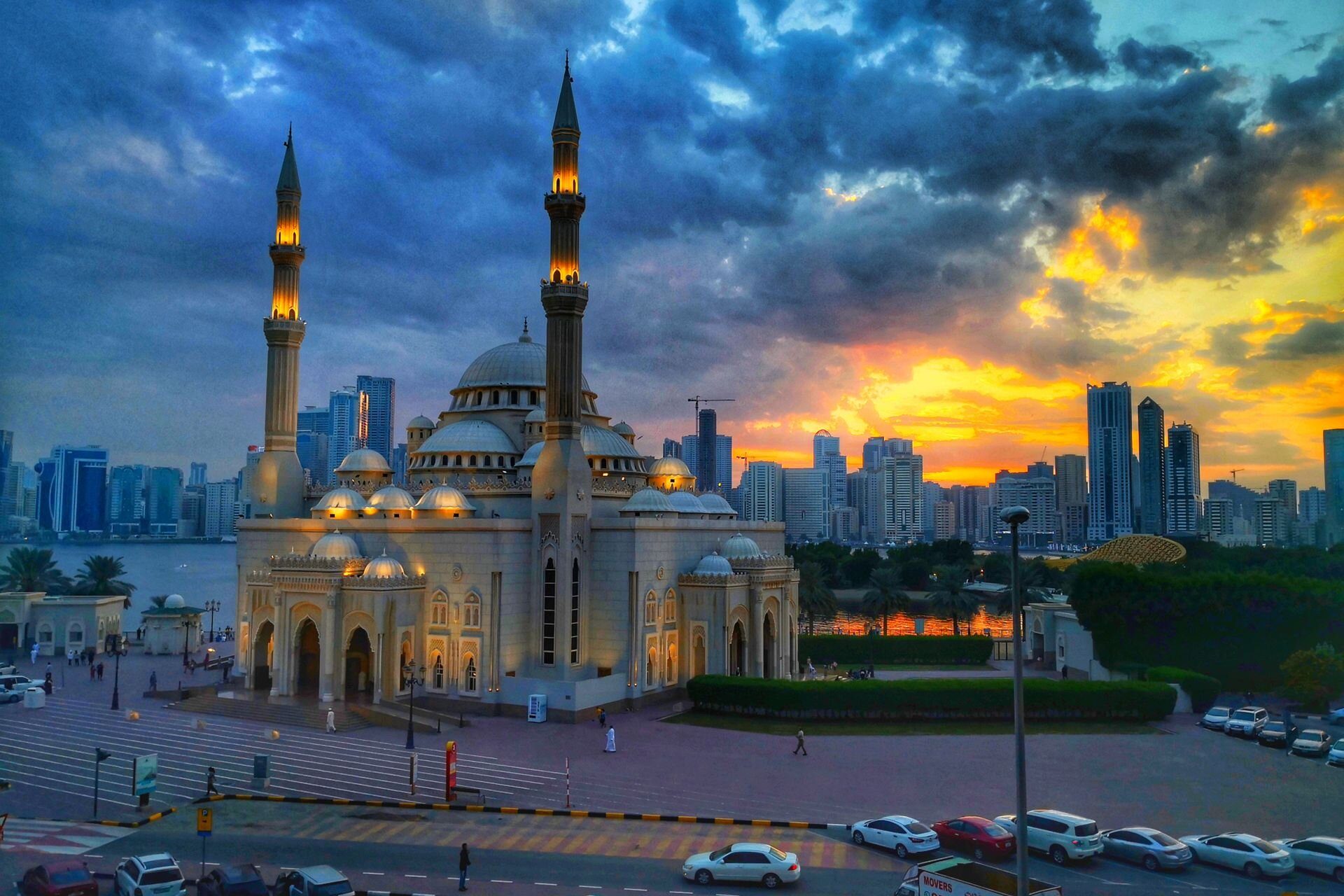 La mezquita Al Noor iluminada al atardecer junto a la laguna Khalid, con el horizonte de Sharjah al fondo