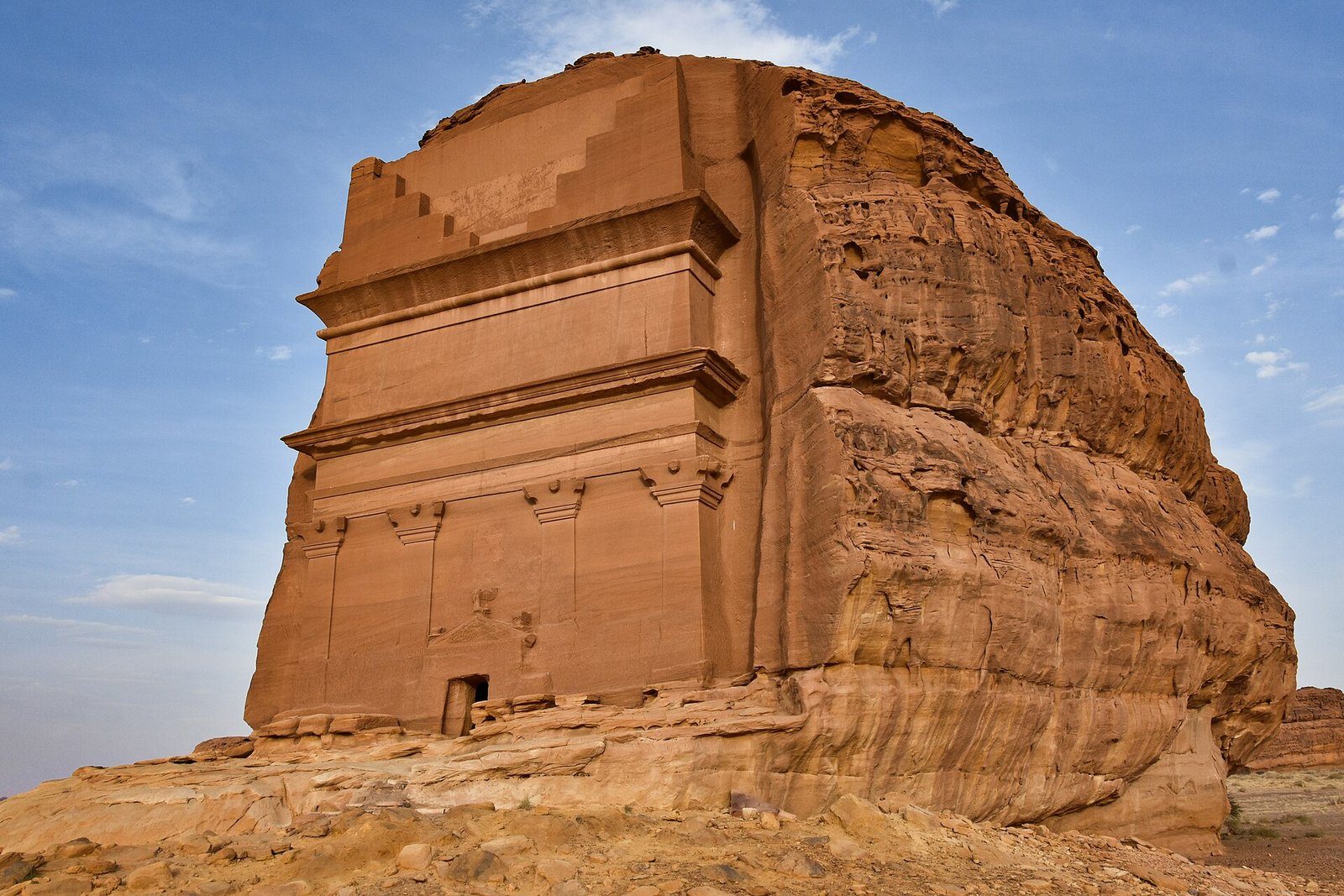 Qasr al-Farid, la solitaria tumba nabatea excavada en un afloramiento de arenisca en Hegra, AlUla, bajo un cielo azul.