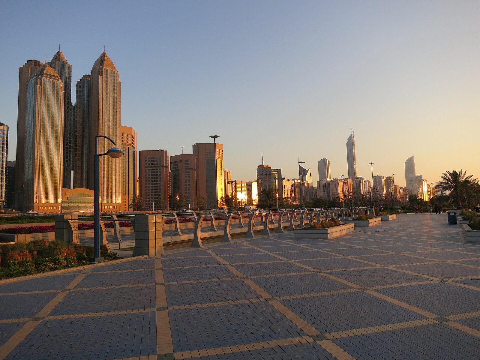 Las torres de la Corniche de Abu Dabi resplandeciendo con la luz dorada del atardecer sobre el paseo marítimo.