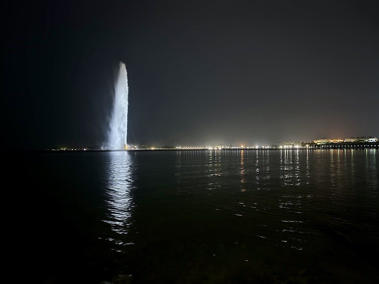 La Fuente del Rey Fahd se eleva sobre el Mar Rojo de noche, con su penacho reflejado en el agua frente a la Corniche de Yeda.