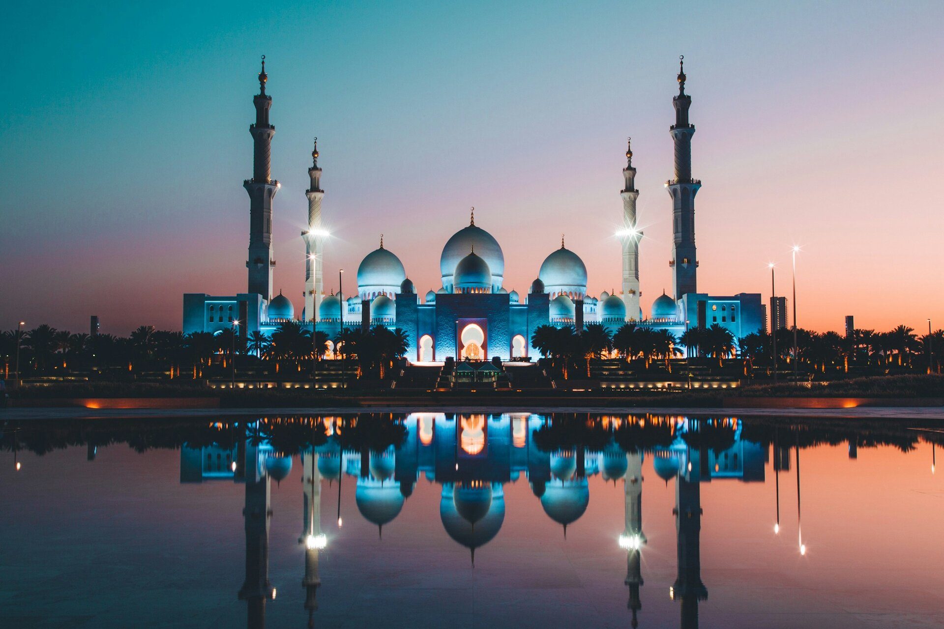 La Gran Mezquita Sheikh Zayed iluminada al anochecer y reflejada en sus estanques, Abu Dabi