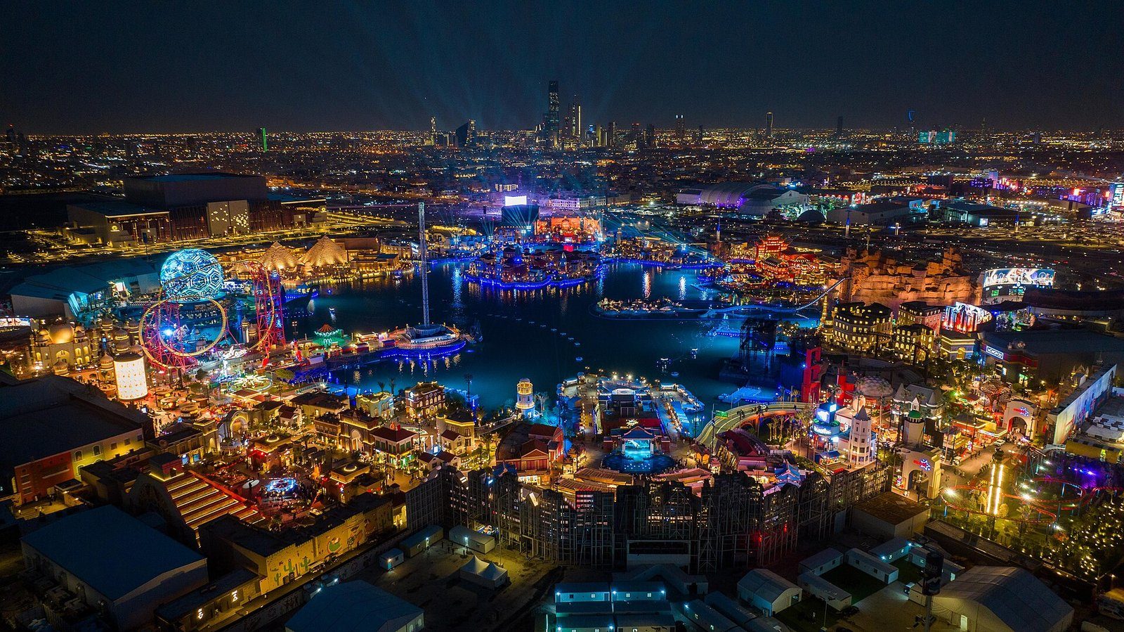 Boulevard World en Riad, resplandeciente de noche alrededor de su lago, con el perfil de la ciudad al fondo