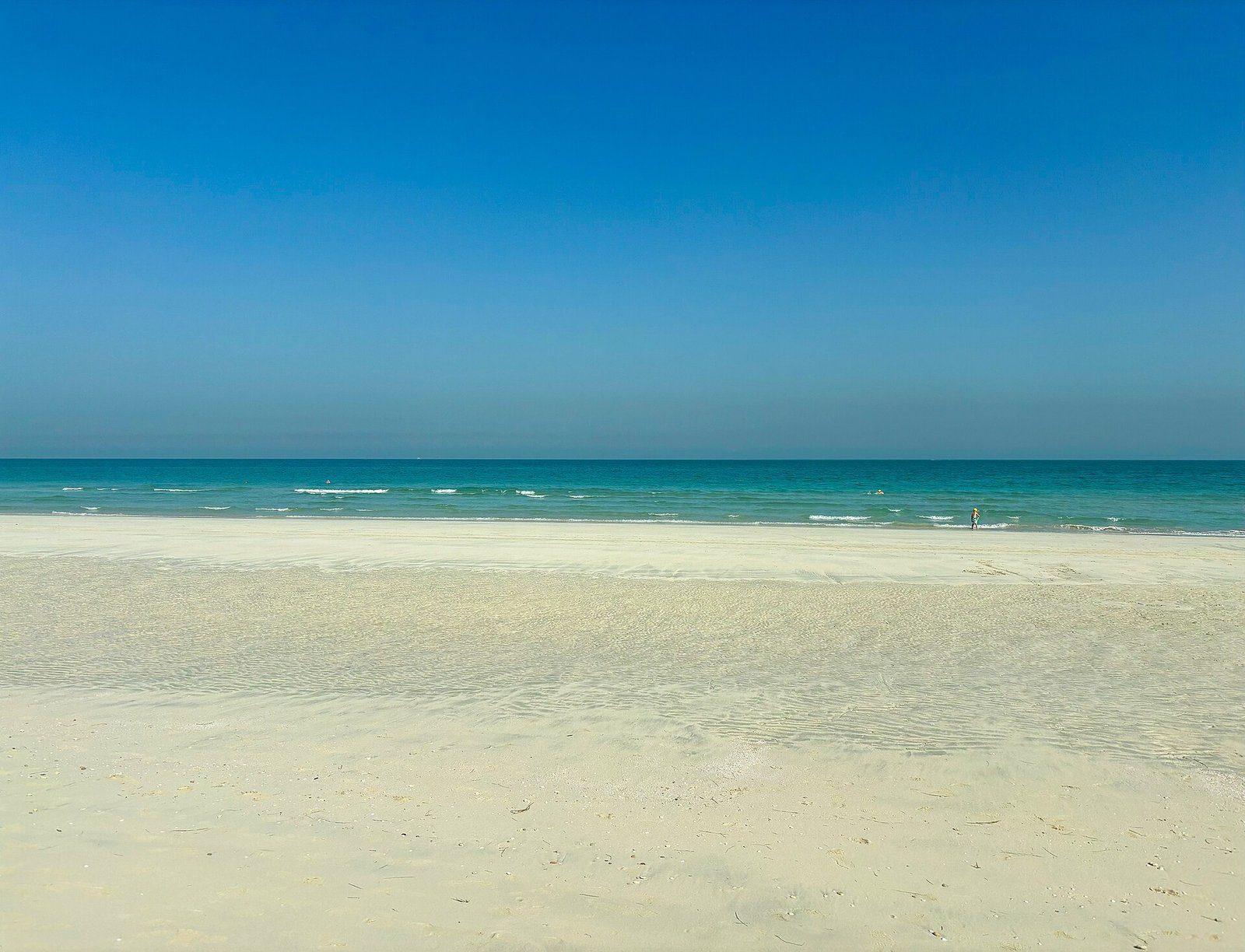 Una mañana tranquila en la amplia playa blanca de la isla de Saadiyat, con aguas turquesas cristalinas y poco profundas