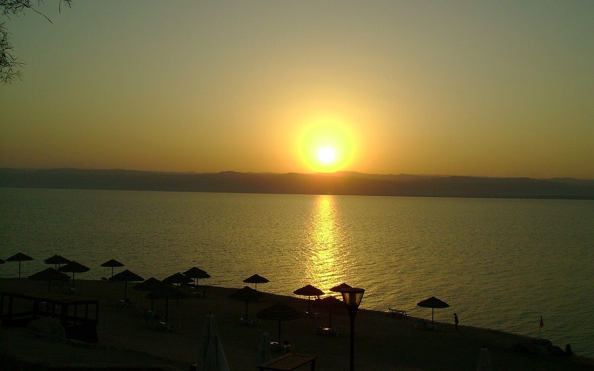 Puesta de sol sobre el Mar Muerto desde la orilla de los resorts jordanos en Sweimeh, donde las terrazas del Kempinski Ishtar descienden hasta el agua