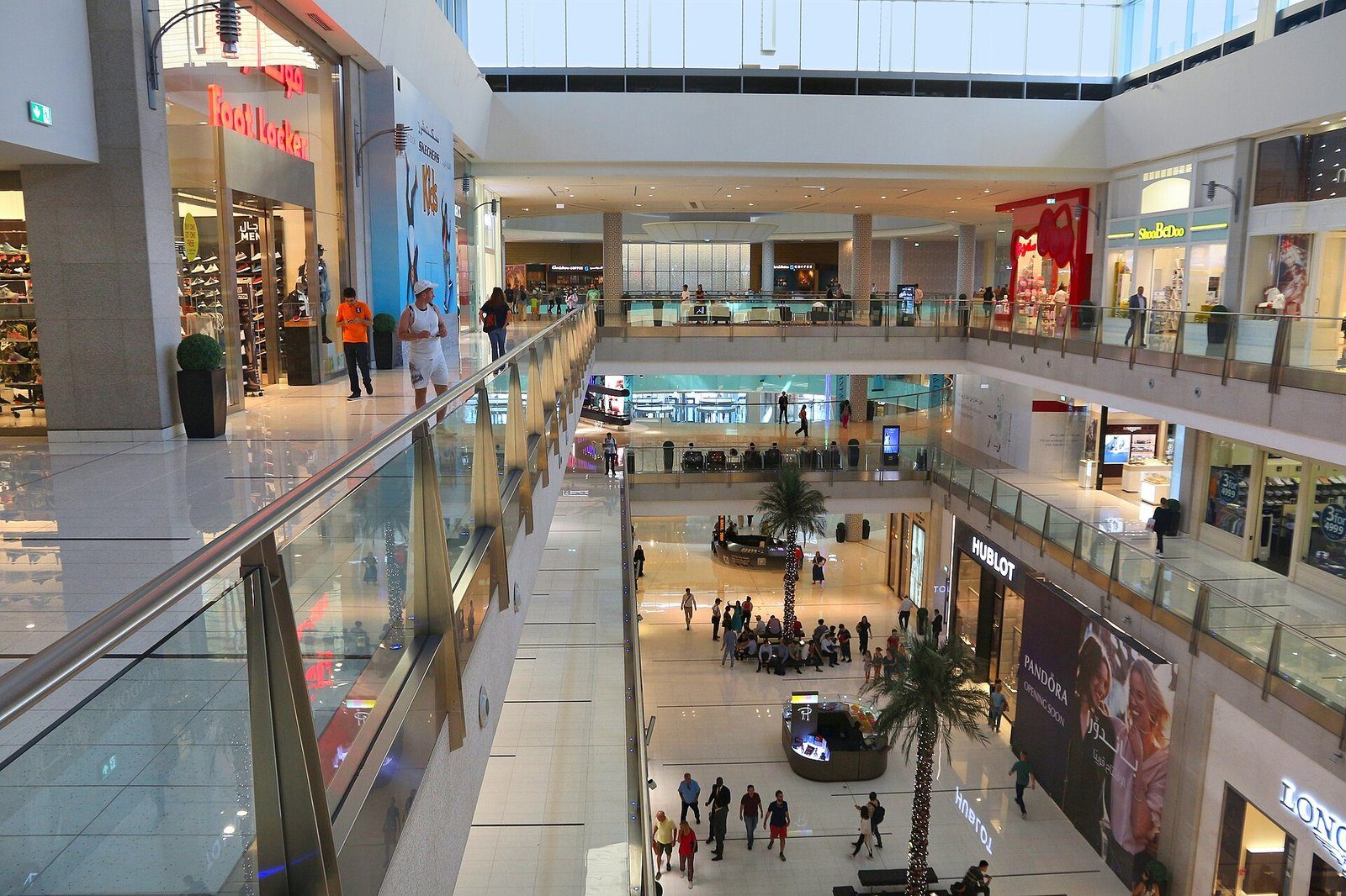 Palmeras que se elevan en el atrio de varias plantas con barandillas de cristal de The Dubai Mall.