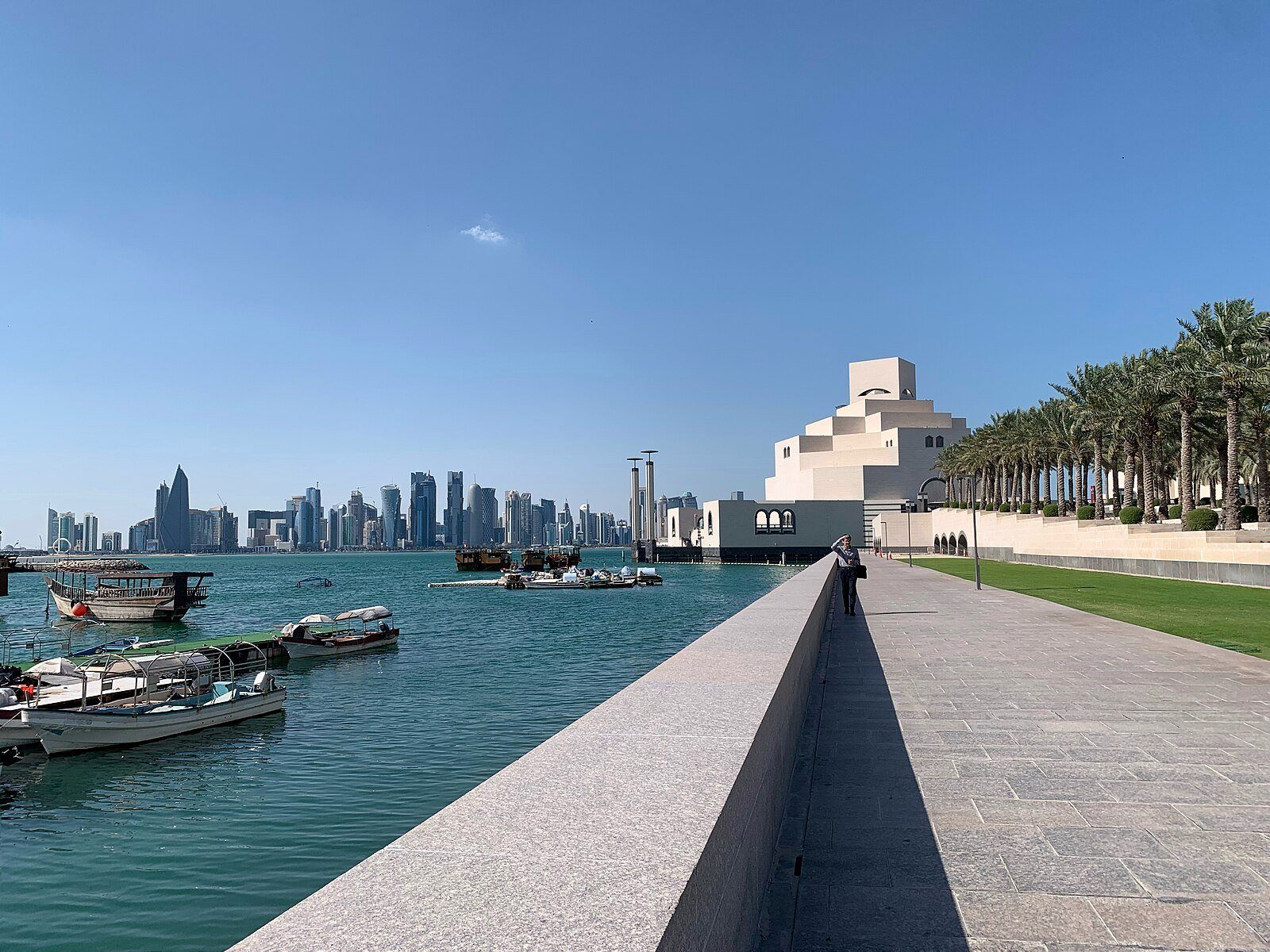 Dhows tradicionales amarrados bajo el Museo de Arte Islámico, con las torres de West Bay de Doha al otro lado de la bahía.