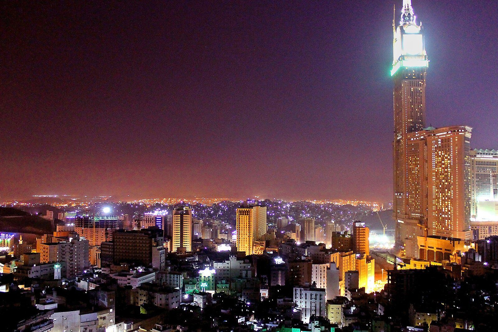 Las luces nocturnas de La Meca vistas desde las montañas circundantes, con la Makkah Royal Clock Tower alzándose a la derecha.