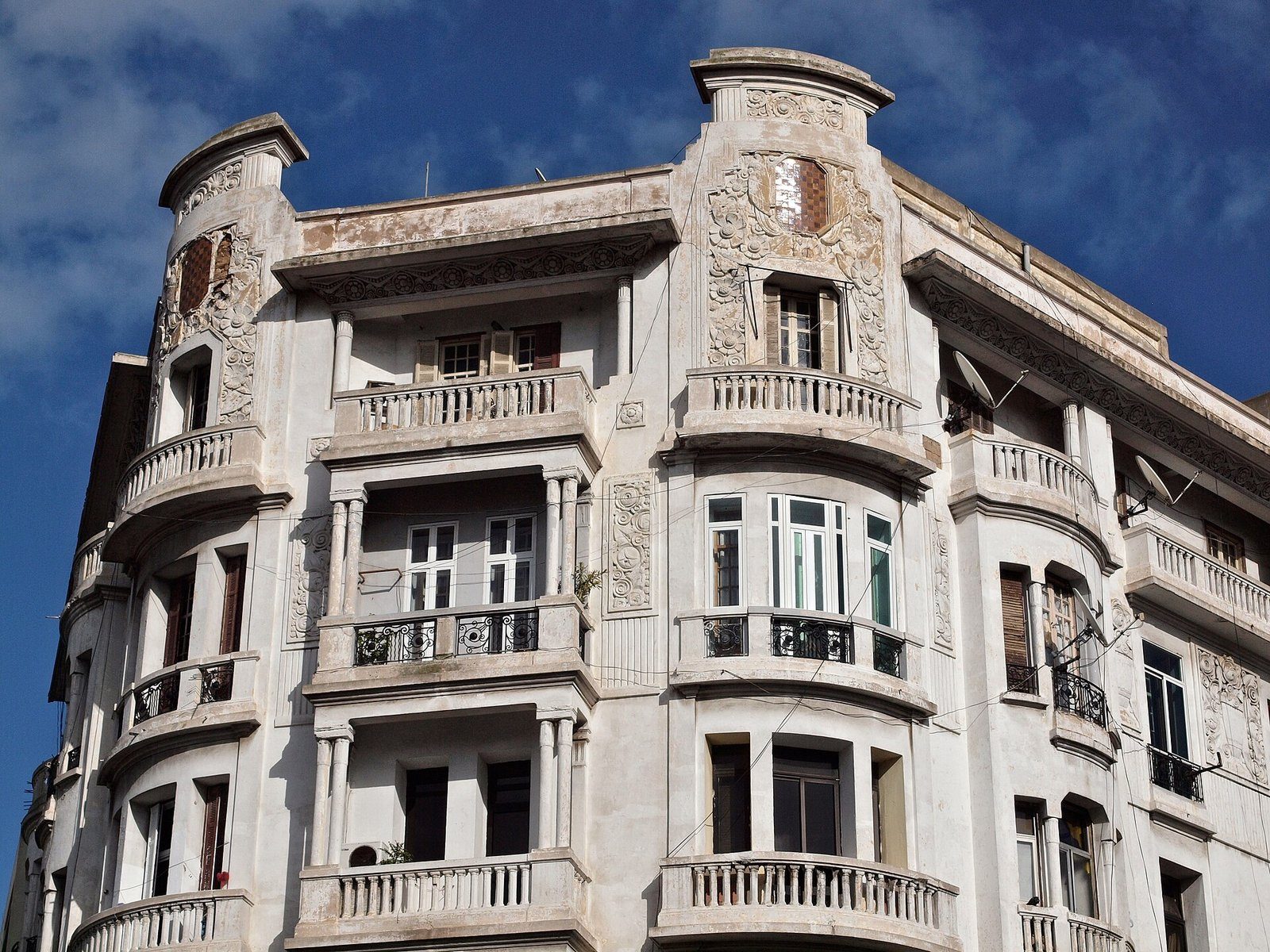 Un ornamentado edificio de viviendas art déco, de color blanco, con balcones esculpidos bajo un cielo azul en el centro de Casablanca.