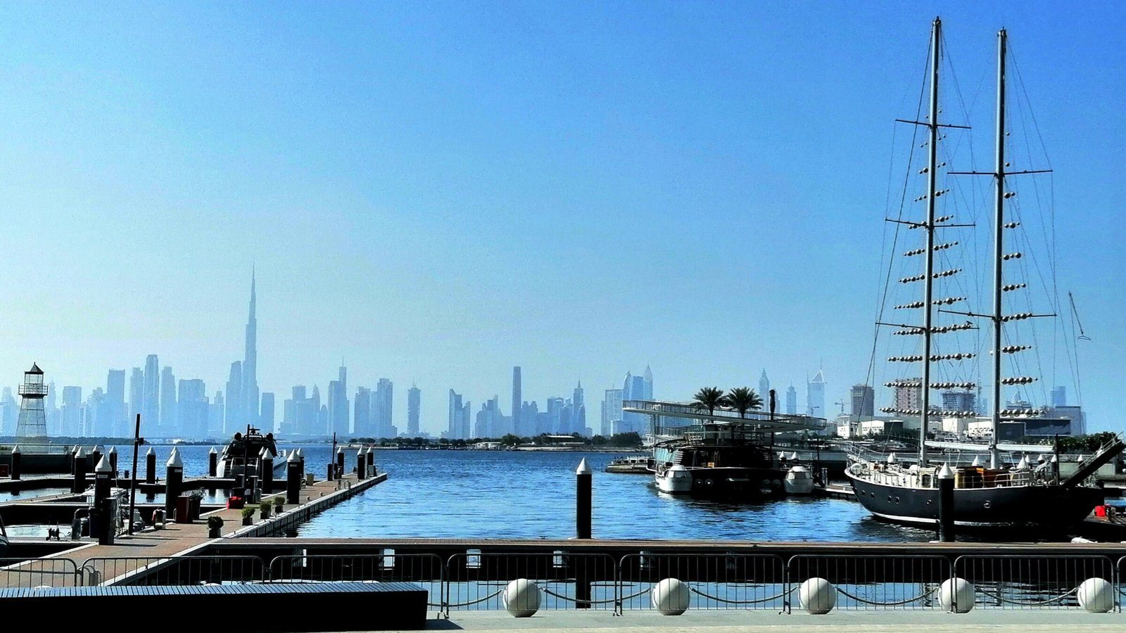 Una goleta de altos mástiles amarrada en el puerto deportivo de Dubai Creek Harbour, con el horizonte de Downtown Dubai al otro lado del agua.