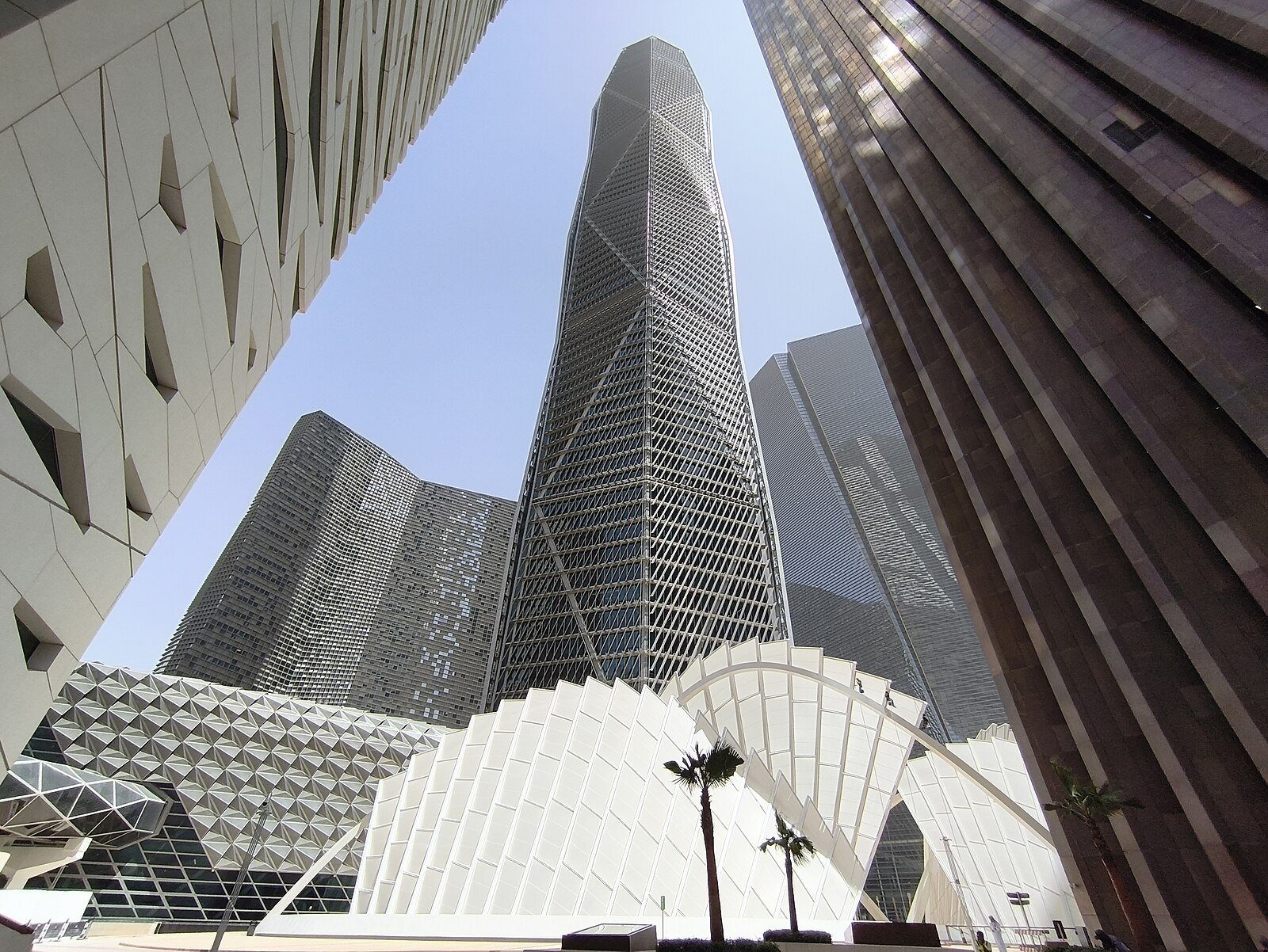 Torres de cristal facetado del King Abdullah Financial District que se alzan sobre esculturales marquesinas blancas y palmeras en Riad.
