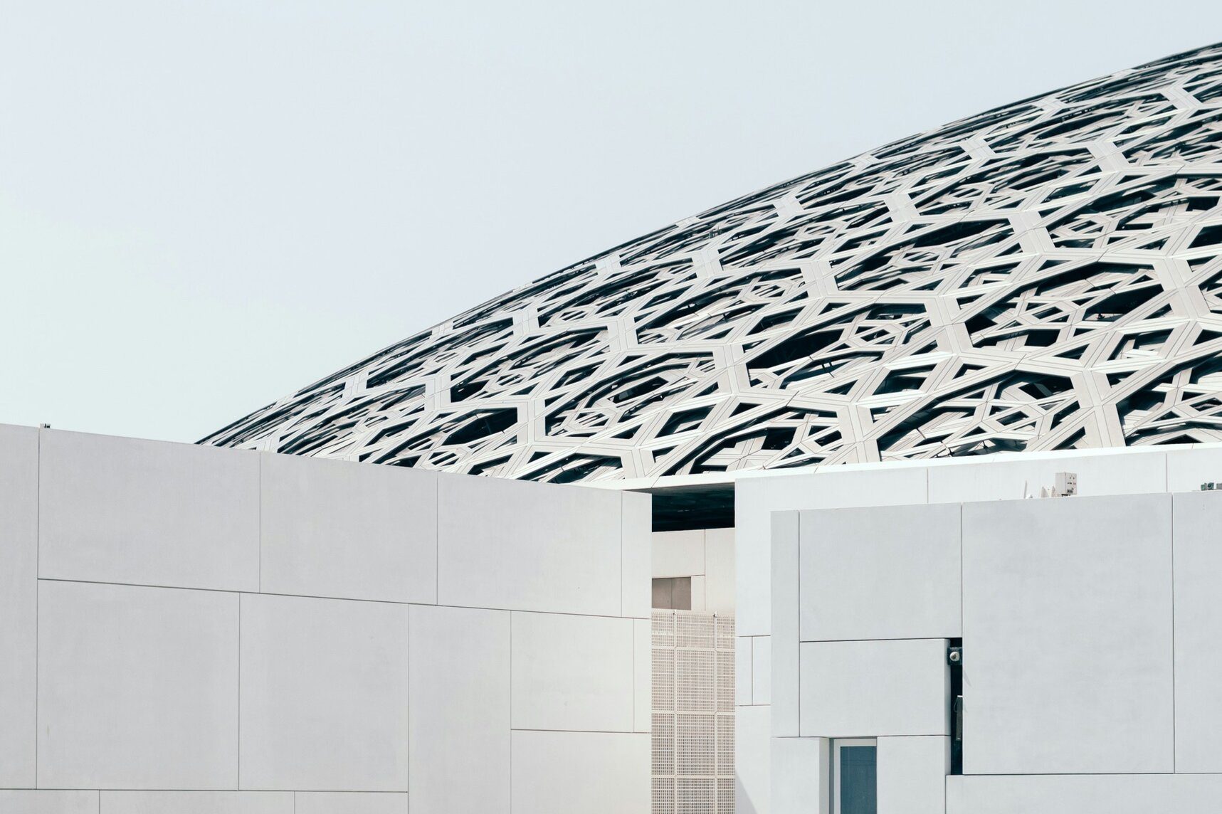 La cúpula de celosía del Louvre Abu Dhabi sobre galerías blancas y el mar, isla de Saadiyat