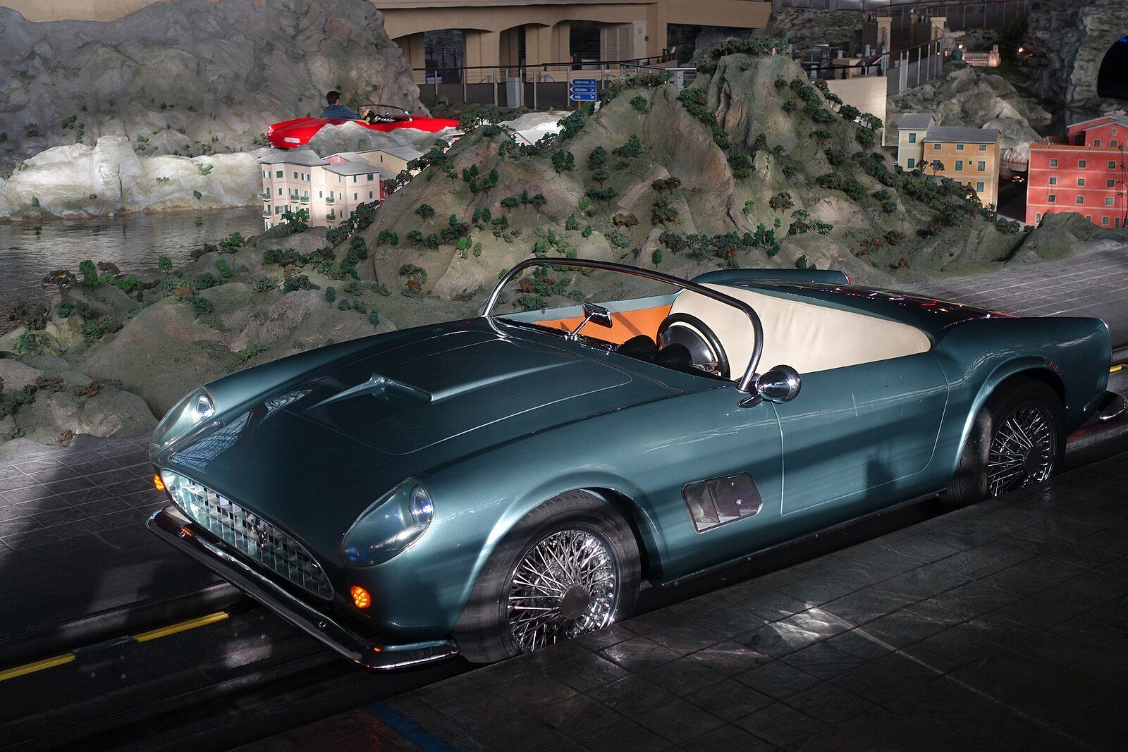 Un Ferrari 250 California Spyder clásico en la atracción Bell'Italia de Ferrari World, ante una costa italiana en miniatura
