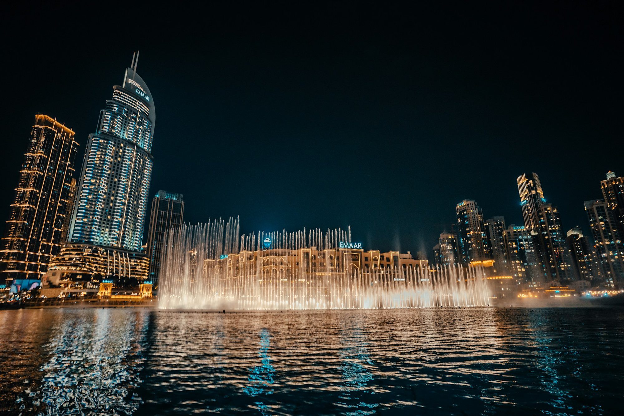 The Dubai Fountain iluminada en dorado de noche junto a Souk Al Bahar