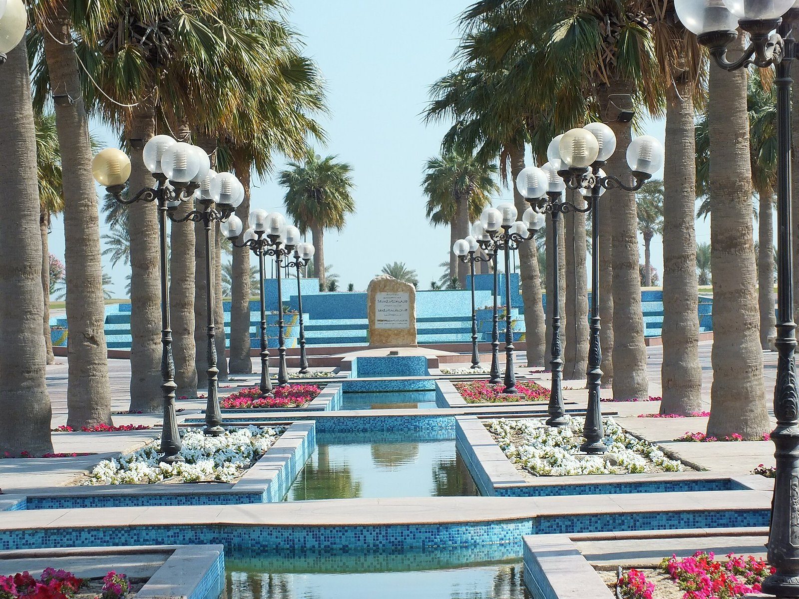 Fuentes y farolas bordeadas de palmeras a lo largo de la Corniche de Al Khobar bajo un cielo despejado, Arabia Saudí.