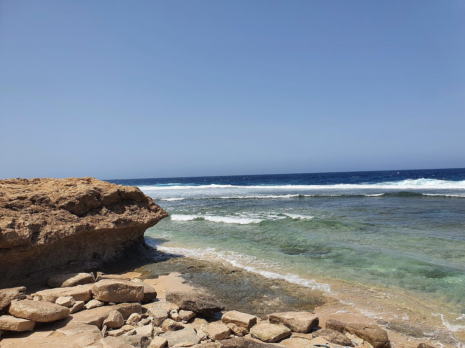 Aguas turquesa transparentes bañando una costa rocosa de piedra caliza en el litoral del Mar Rojo en Umluj, Arabia Saudí.