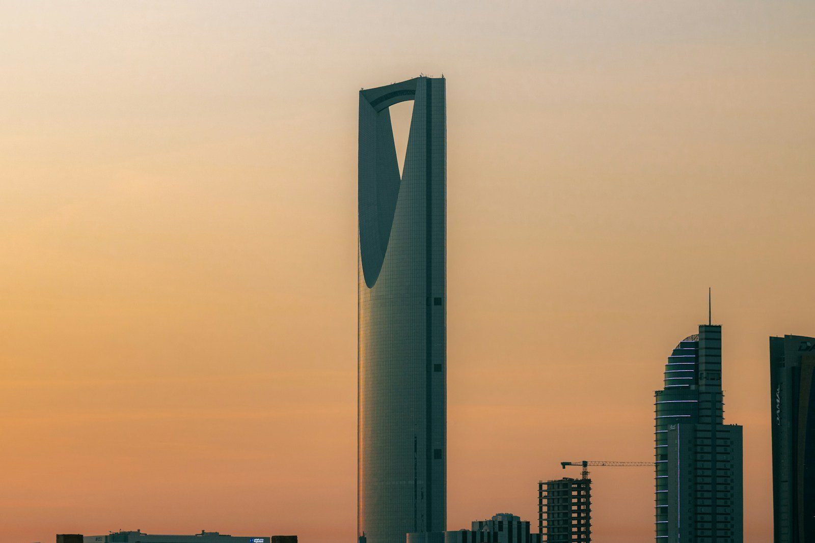 La silueta de la torre del Kingdom Centre ante un cálido cielo ámbar al atardecer en Riad.