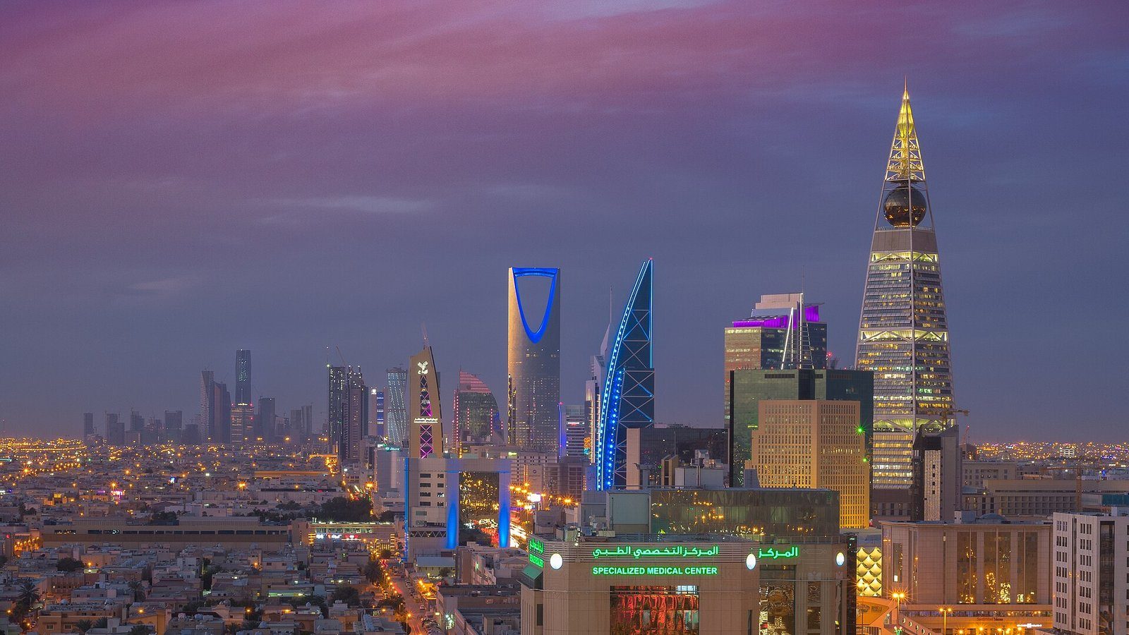 El horizonte de Riad al anochecer, con las torres Kingdom Centre y Al Faisaliah iluminadas contra un cielo violeta.