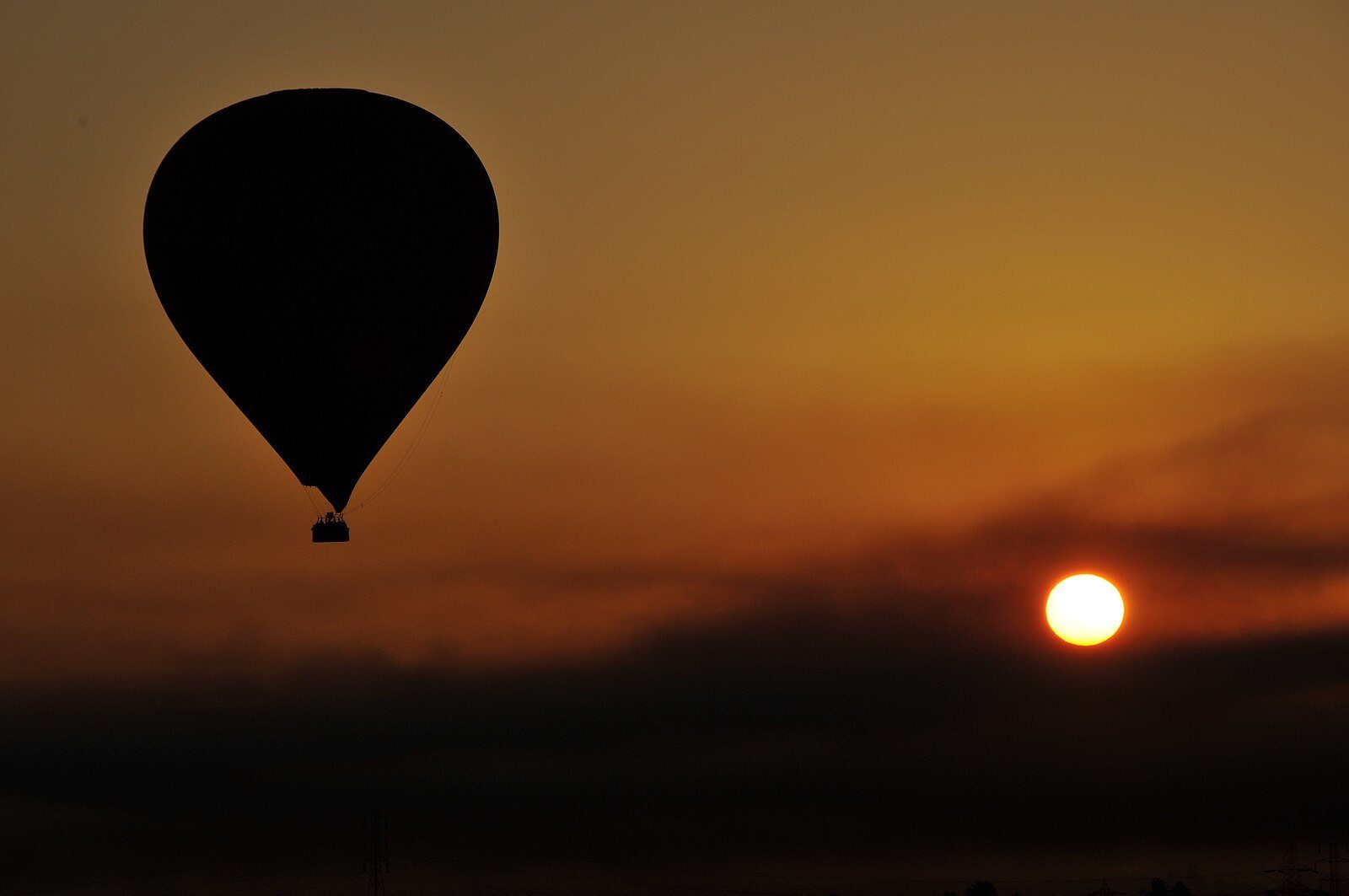 Un globo aerostático recortado contra un amanecer resplandeciente sobre la orilla occidental de Luxor, Egipto.