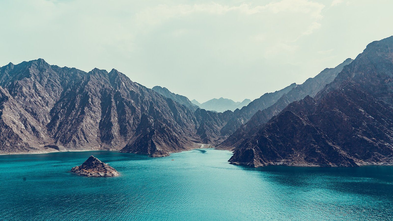 Aguas turquesas de la presa de Hatta entre las escarpadas montañas Hajar, Dubái