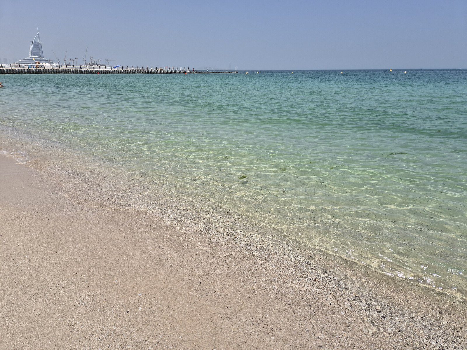 Aguas turquesa transparentes y poco profundas a lo largo de Kite Beach en Dubái, con el Burj Al Arab en el horizonte