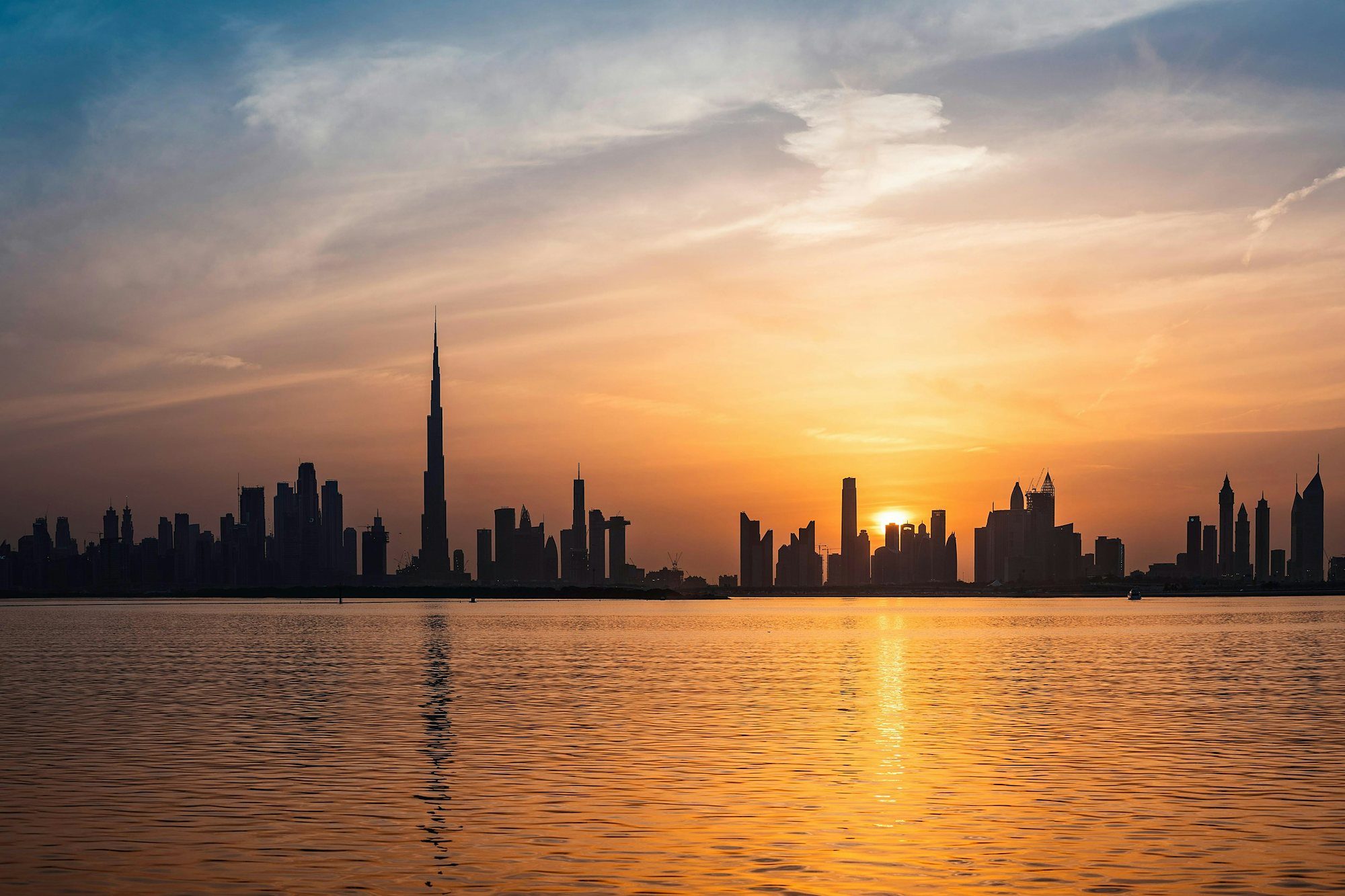 El perfil urbano de Dubái y el Burj Khalifa al atardecer sobre el agua