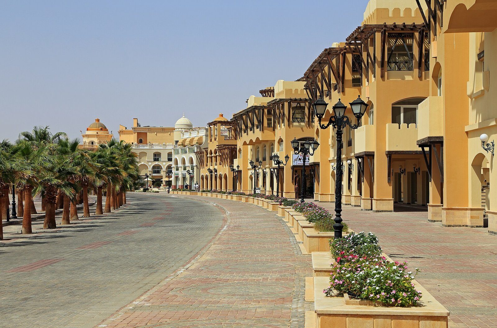 Un paseo bordeado de palmeras con edificios porticados de resorts en Sahl Hasheesh, en la costa egipcia del Mar Rojo.