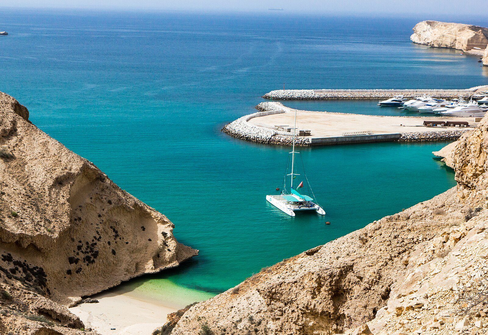 Un catamarán fondeado en una cala turquesa junto al puerto deportivo del resort Shangri-La Barr Al Jissah, en la costa de Mascate.