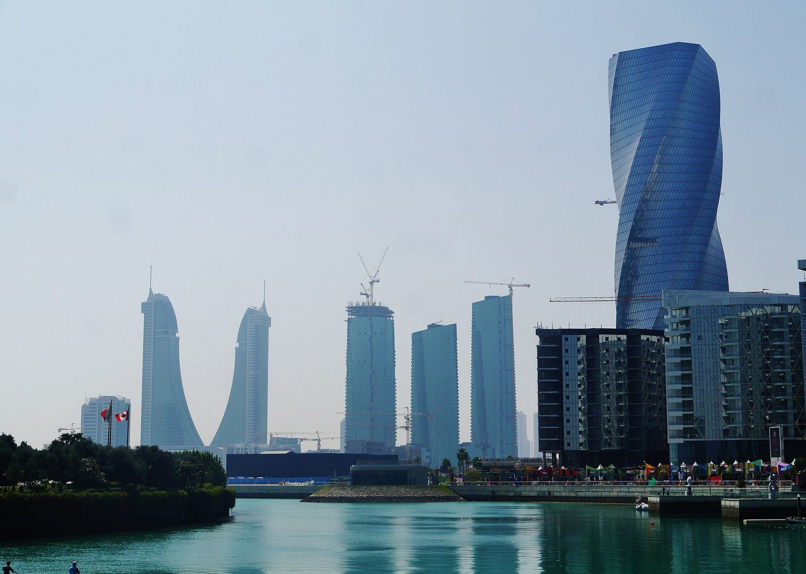 Las torres retorcidas de Bahrain Bay reflejadas en el agua en calma del frente marítimo de Manama.