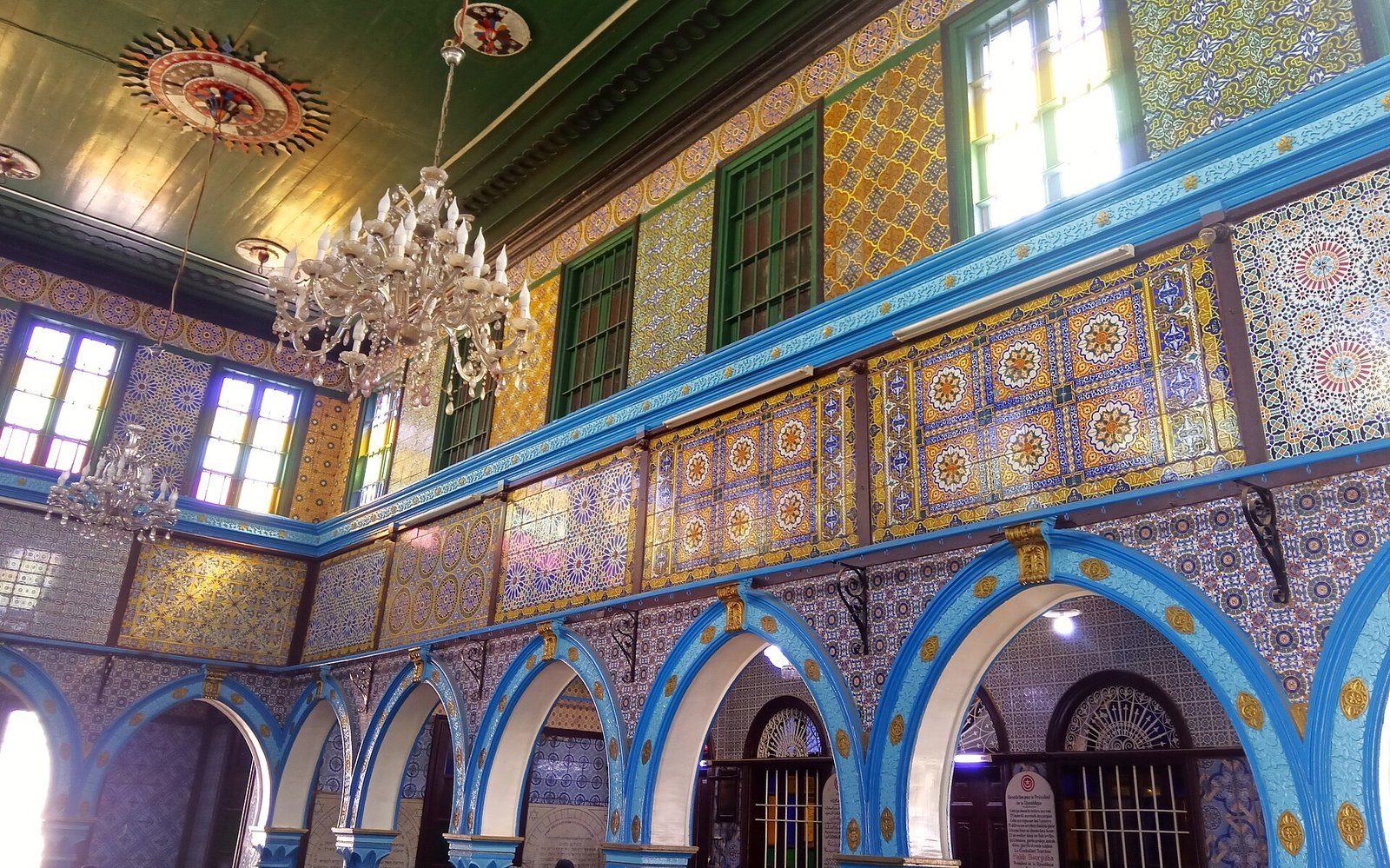 Arcos azules, azulejos pintados y lámparas de cristal llenan el interior de la sinagoga de El Ghriba en Djerba, Túnez.