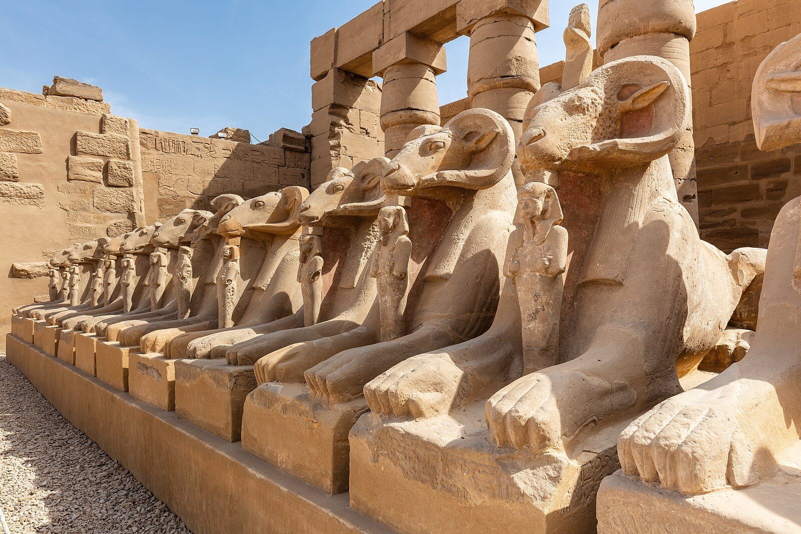 La avenida de esfinges con cabeza de carnero del complejo del Templo de Karnak en Luxor bajo un cielo azul.