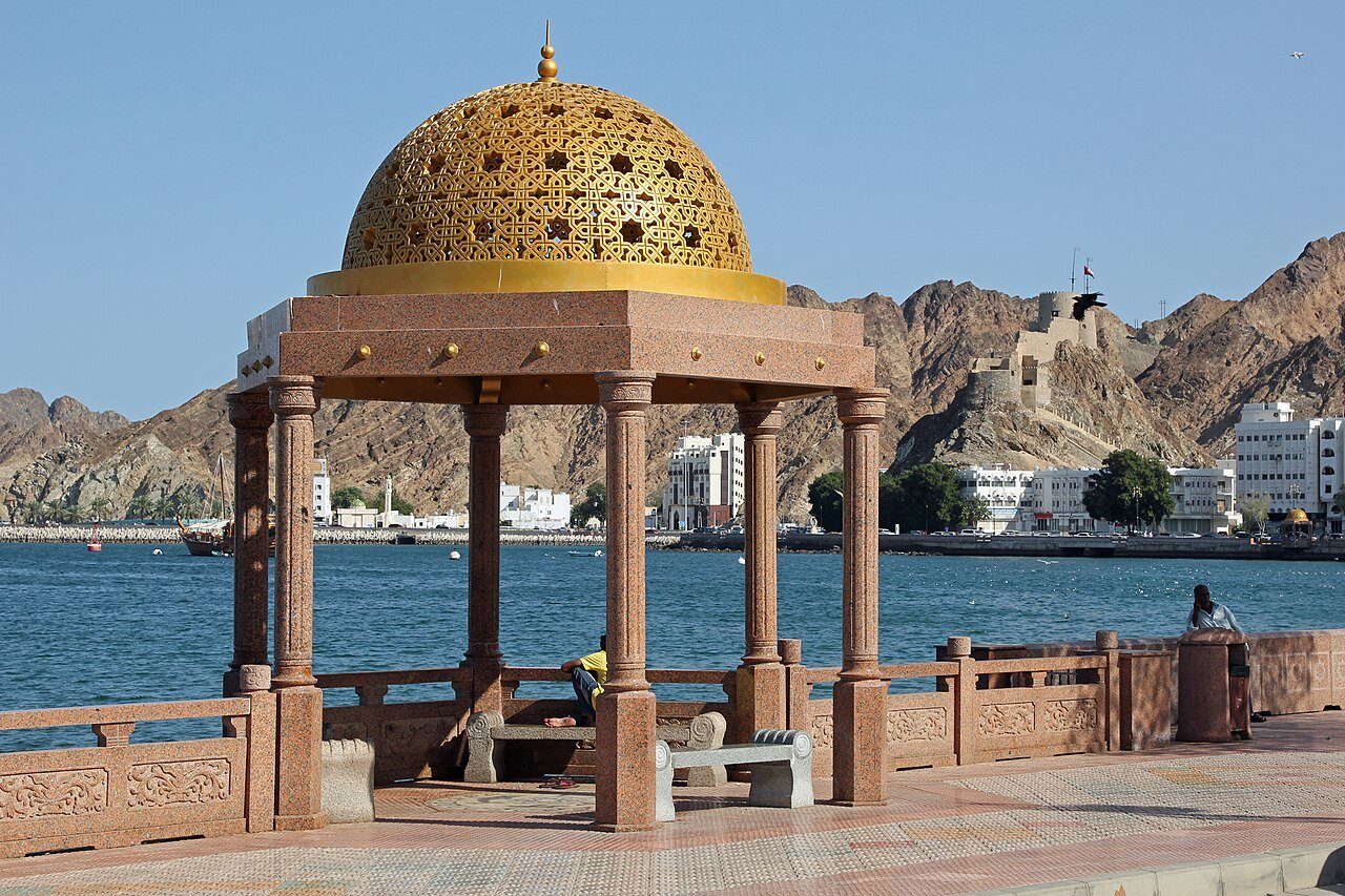 Un pabellón con cúpula dorada en la Corniche de Muttrah, en Mascate, con el puerto y las montañas al fondo.