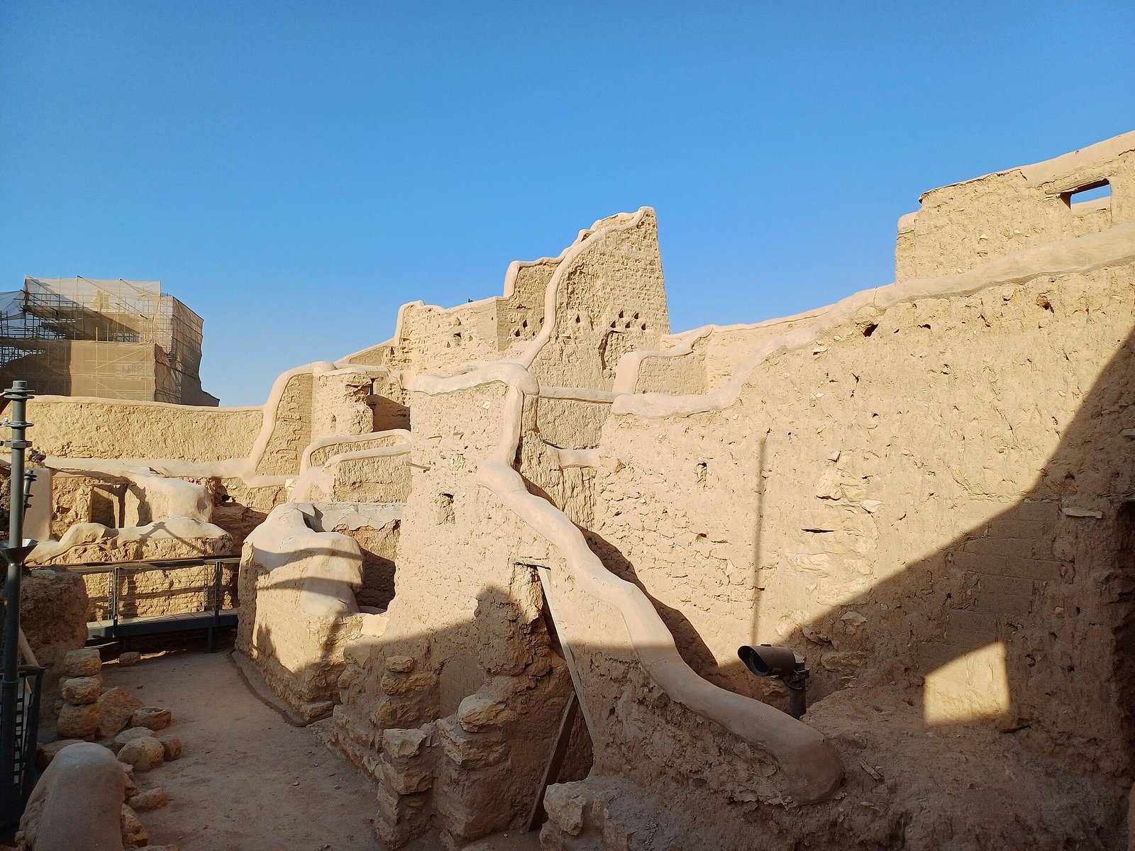 Muros de adobe erosionados del distrito de At-Turaif en Diriyah, Riad, bajo un cielo azul intenso.