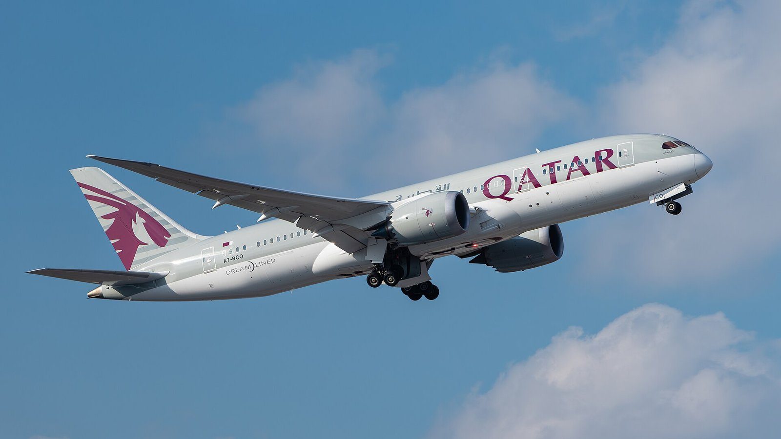 Un Boeing 787 Dreamliner de Qatar Airways ascendiendo hacia un cielo azul intenso tras el despegue.