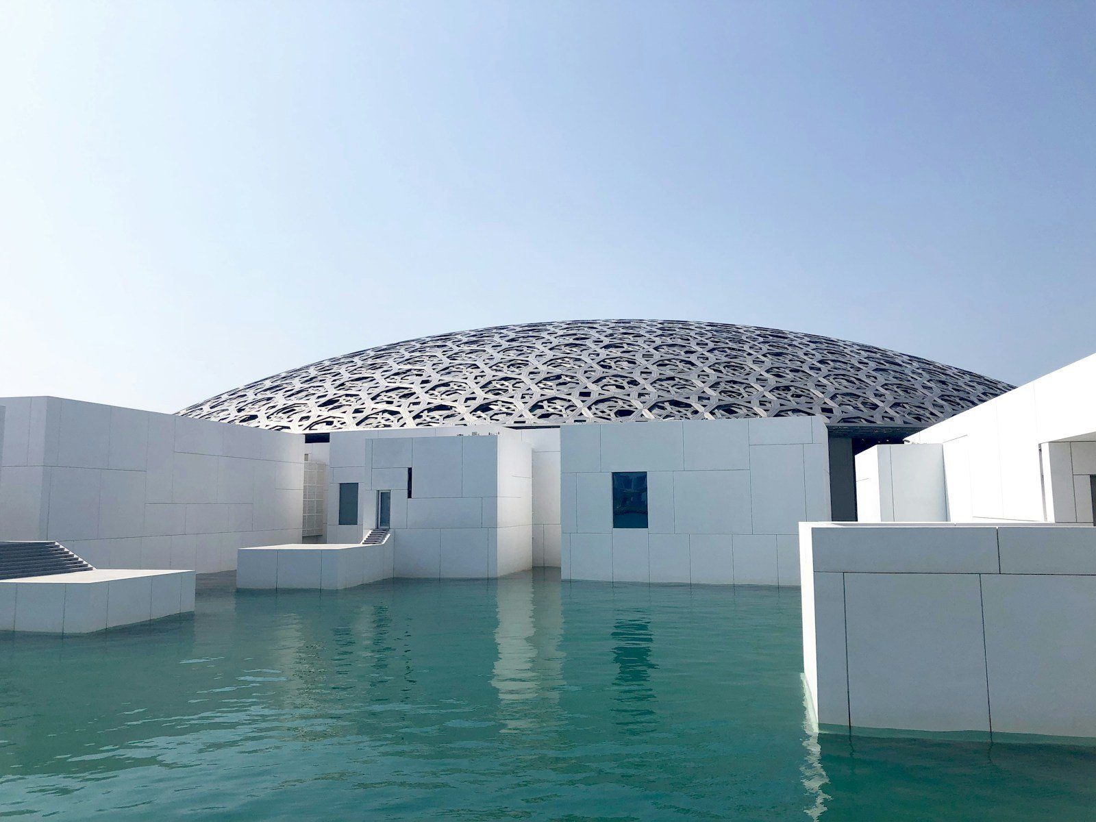 La cúpula plateada de celosía del Louvre Abu Dhabi, que parece flotar sobre galerías blancas y aguas en calma en la isla de Saadiyat.
