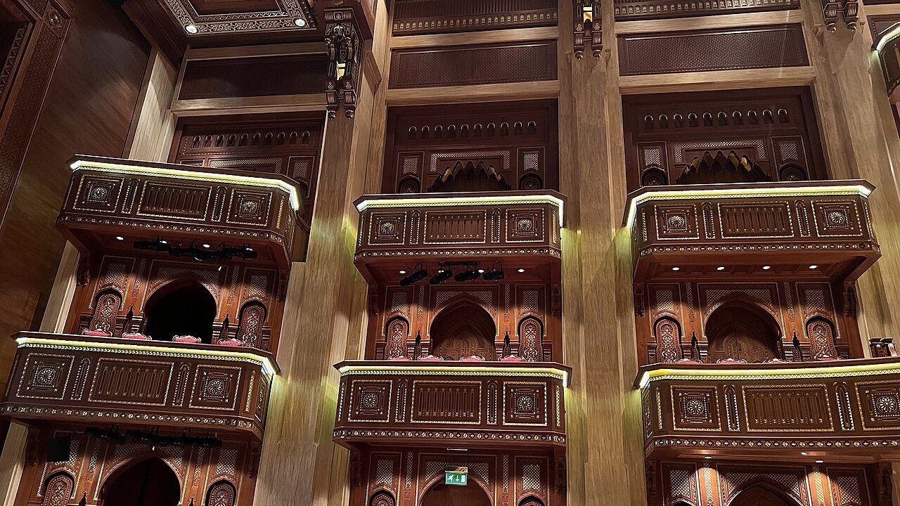 Hileras de palcos de madera tallada con detalles dorados en el auditorio de la Royal Opera House Muscat.