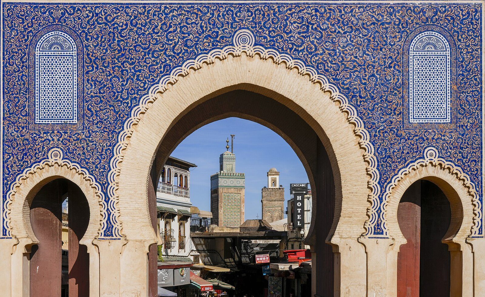 El arco de herradura de azulejos azules de Bab Bou Jeloud enmarca el minarete de la madrasa Bou Inania en Fez.