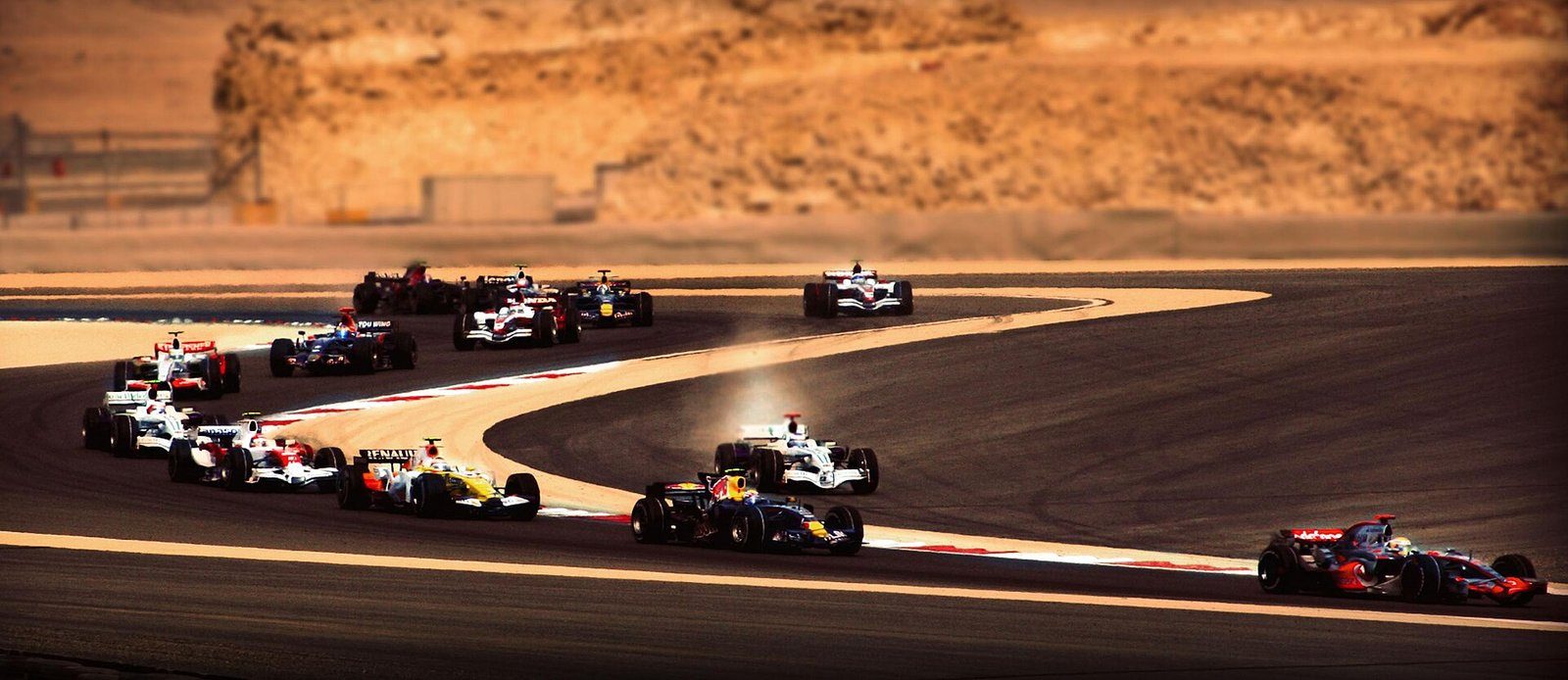 Monoplazas de Fórmula 1 trazando las primeras curvas del Gran Premio de Baréin en Sakhir con la luz del atardecer