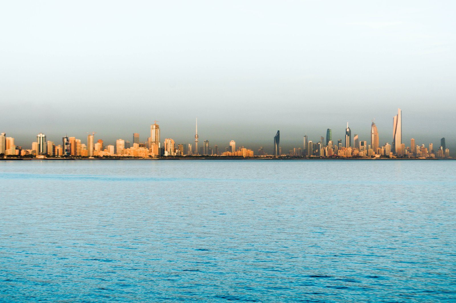El perfil urbano de la ciudad de Kuwait recibiendo la primera luz sobre las aguas tranquilas del Golfo.