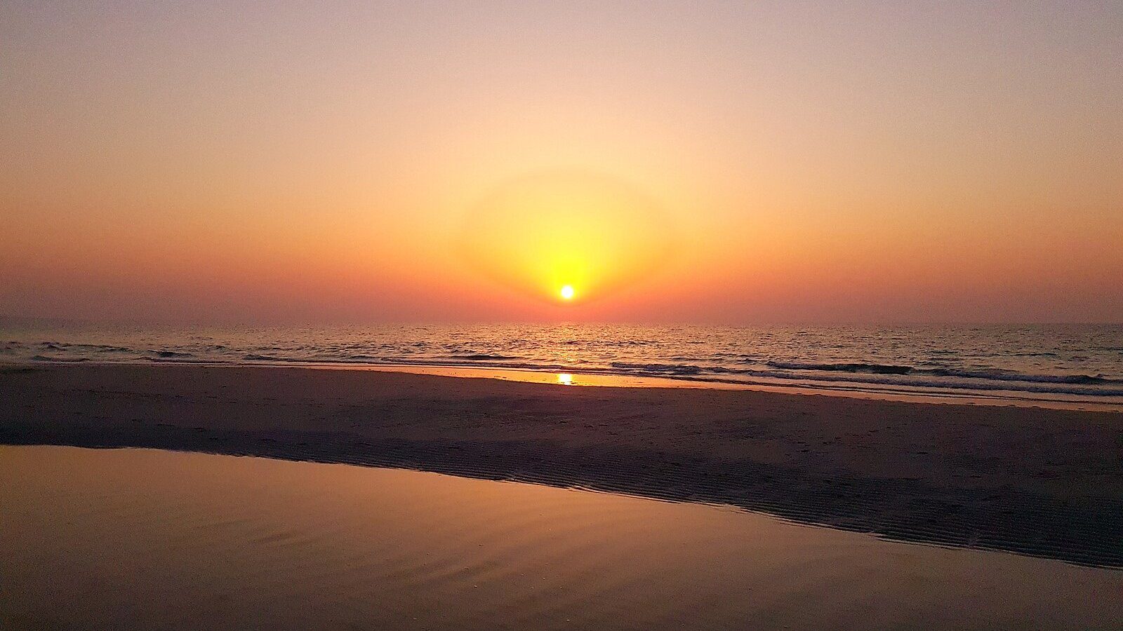 El sol poniéndose sobre el Golfo, dorando la arena húmeda de Saadiyat Beach, Abu Dabi