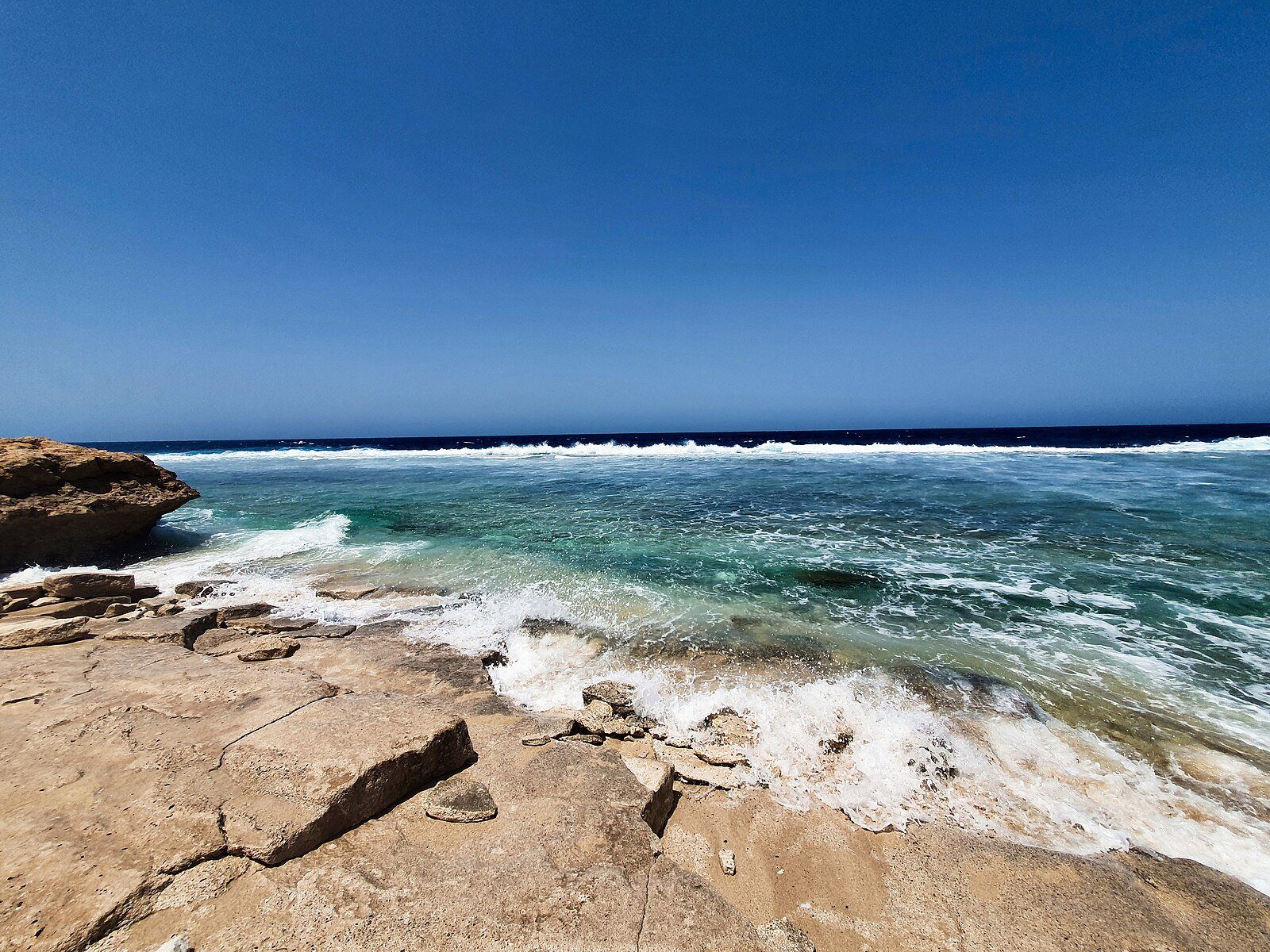 Olas que rompen sobre una plataforma de piedra caliza en aguas turquesas de la costa del Mar Rojo en Umluj, puerta de entrada a los resorts de The Red Sea.