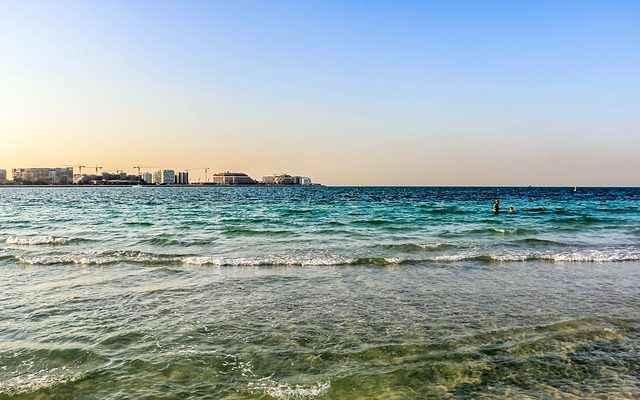La isla Jumeira Bay vista al otro lado del agua desde una playa de Jumeirah al atardecer