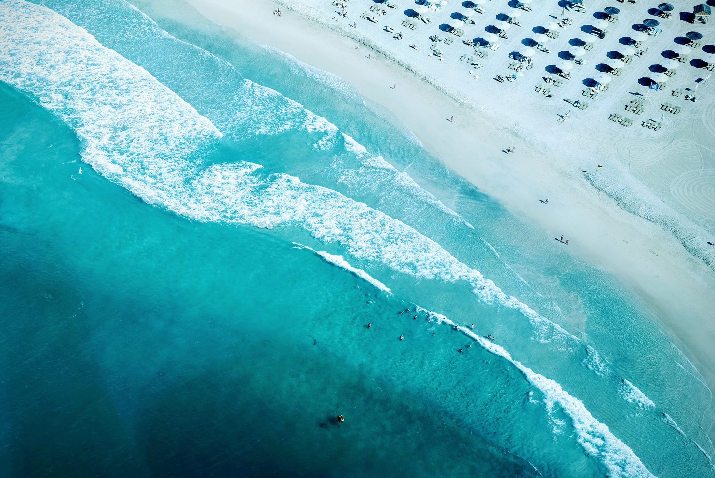 Olas turquesa rompen en una playa de arena blanca en Dubái, vista desde lo alto