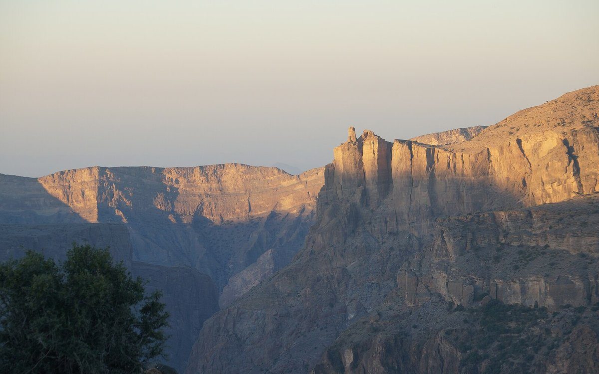 El amanecer ilumina las escarpadas paredes del cañón de Jebel Akhdar, el escenario al borde del desfiladero que domina Alila Jabal Akhdar