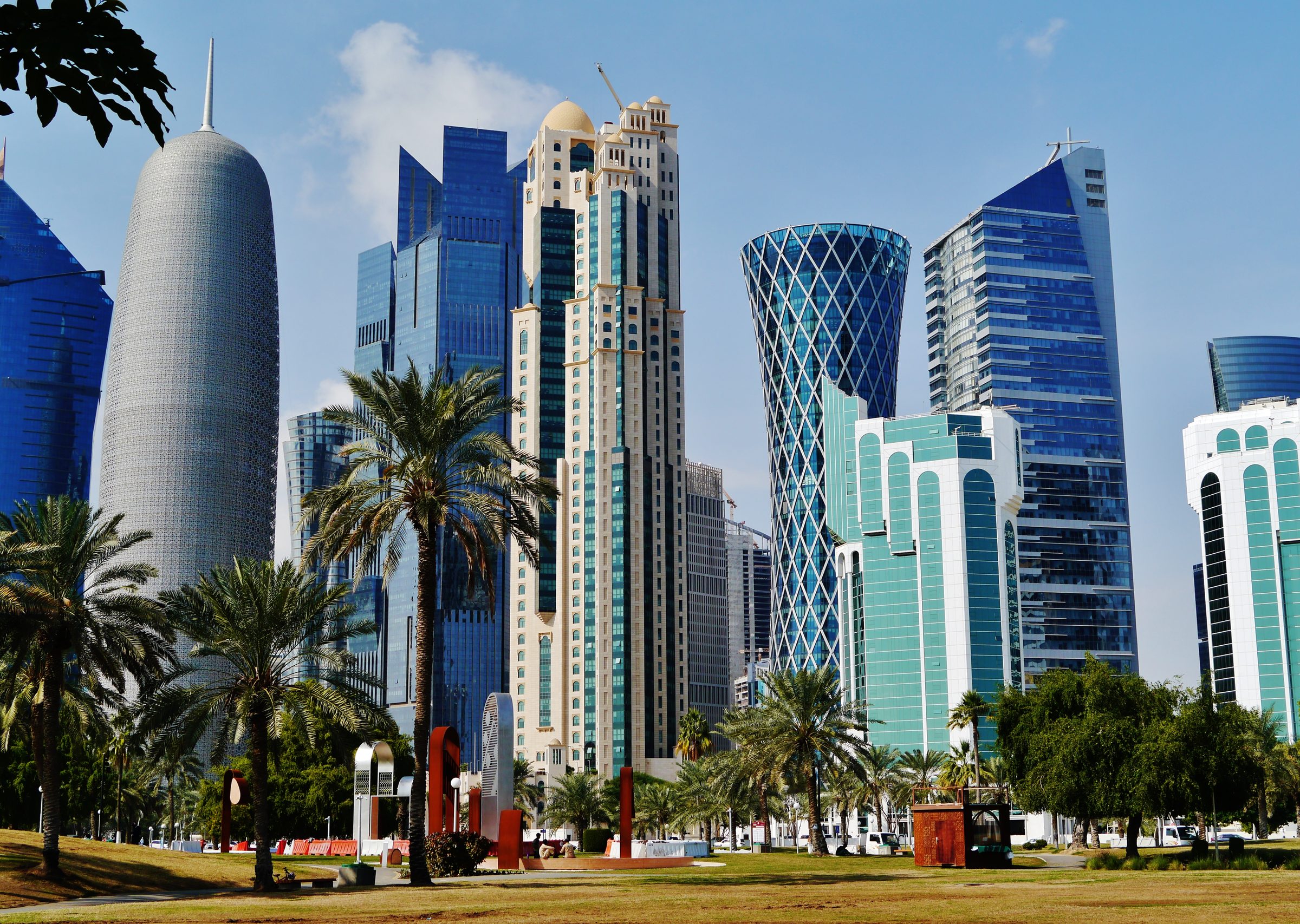 Las torres de cristal del perfil urbano de Doha sobre jardines flanqueados de palmeras