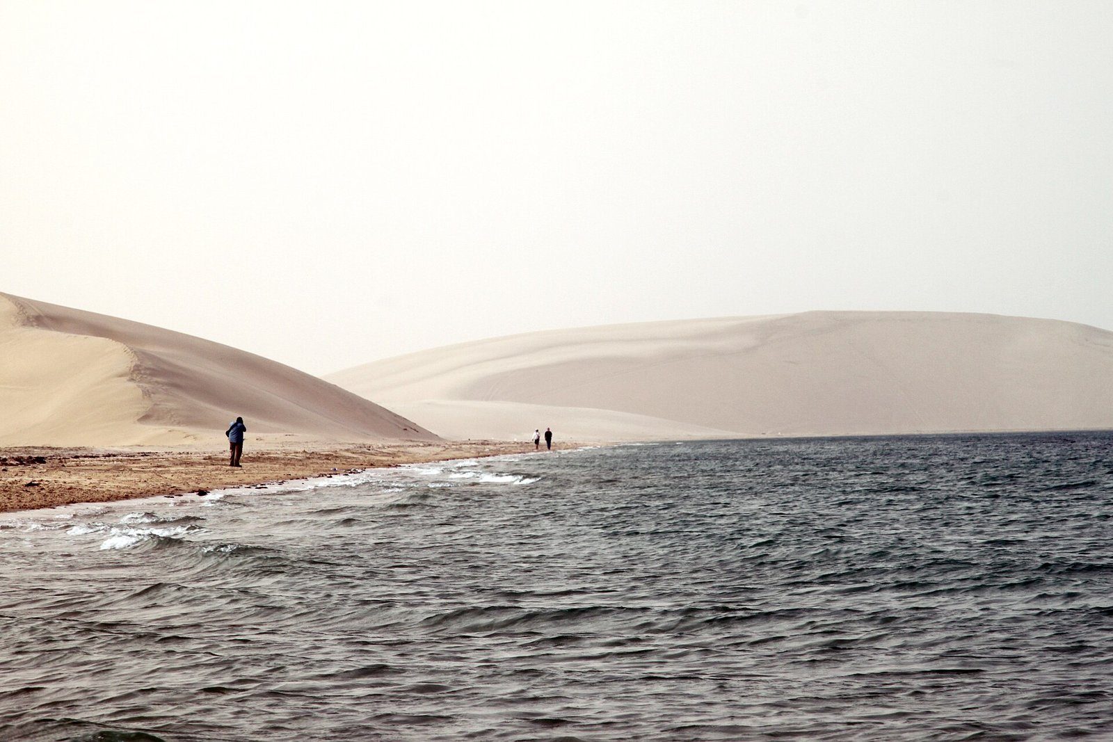 Dunas de arena clara que descienden hasta el agua en Khor Al Adaid, el Mar Interior del sur de Catar.