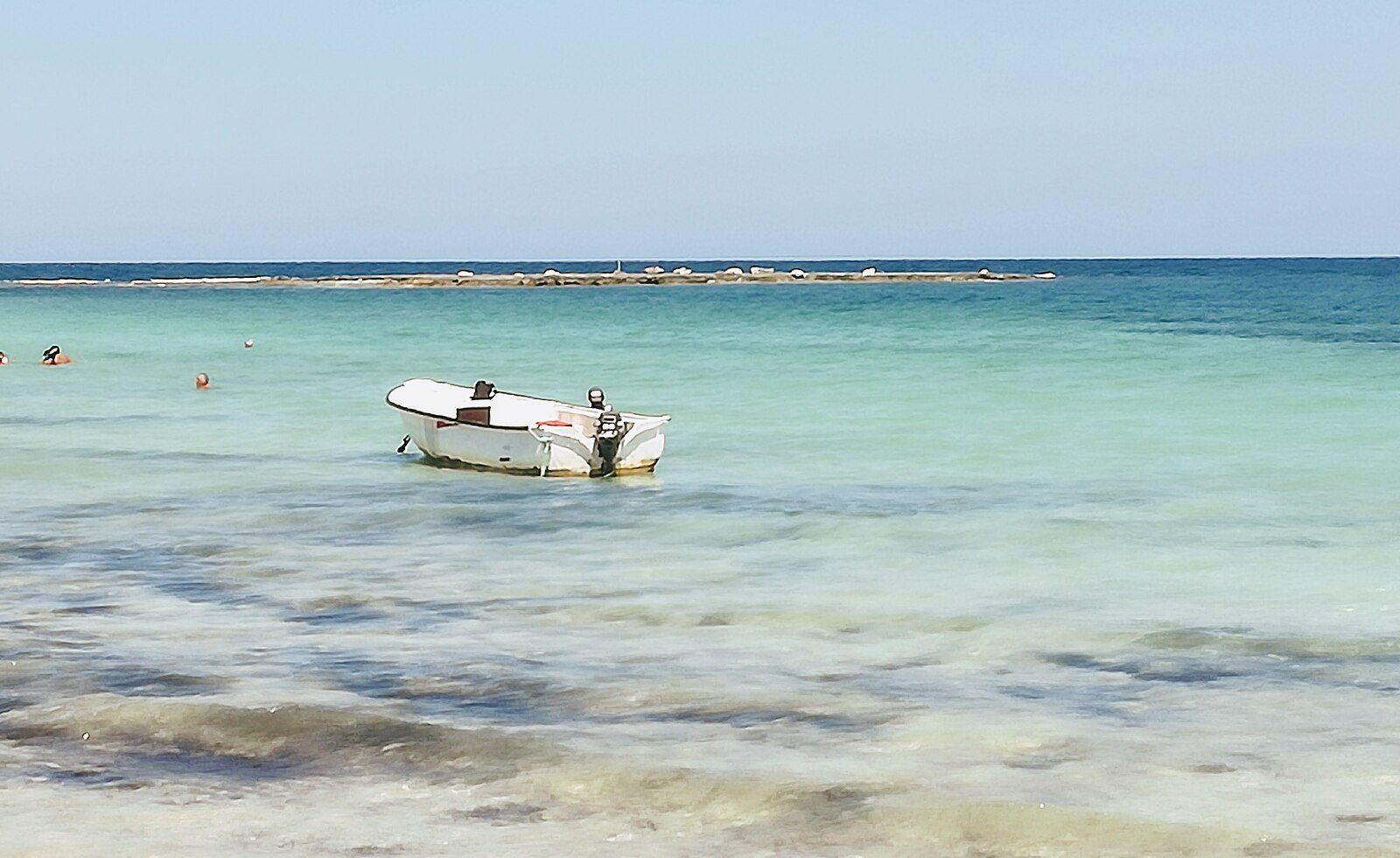 Una pequeña barca descansando sobre aguas turquesas cristalinas y poco profundas frente a una playa de Yerba, Túnez.