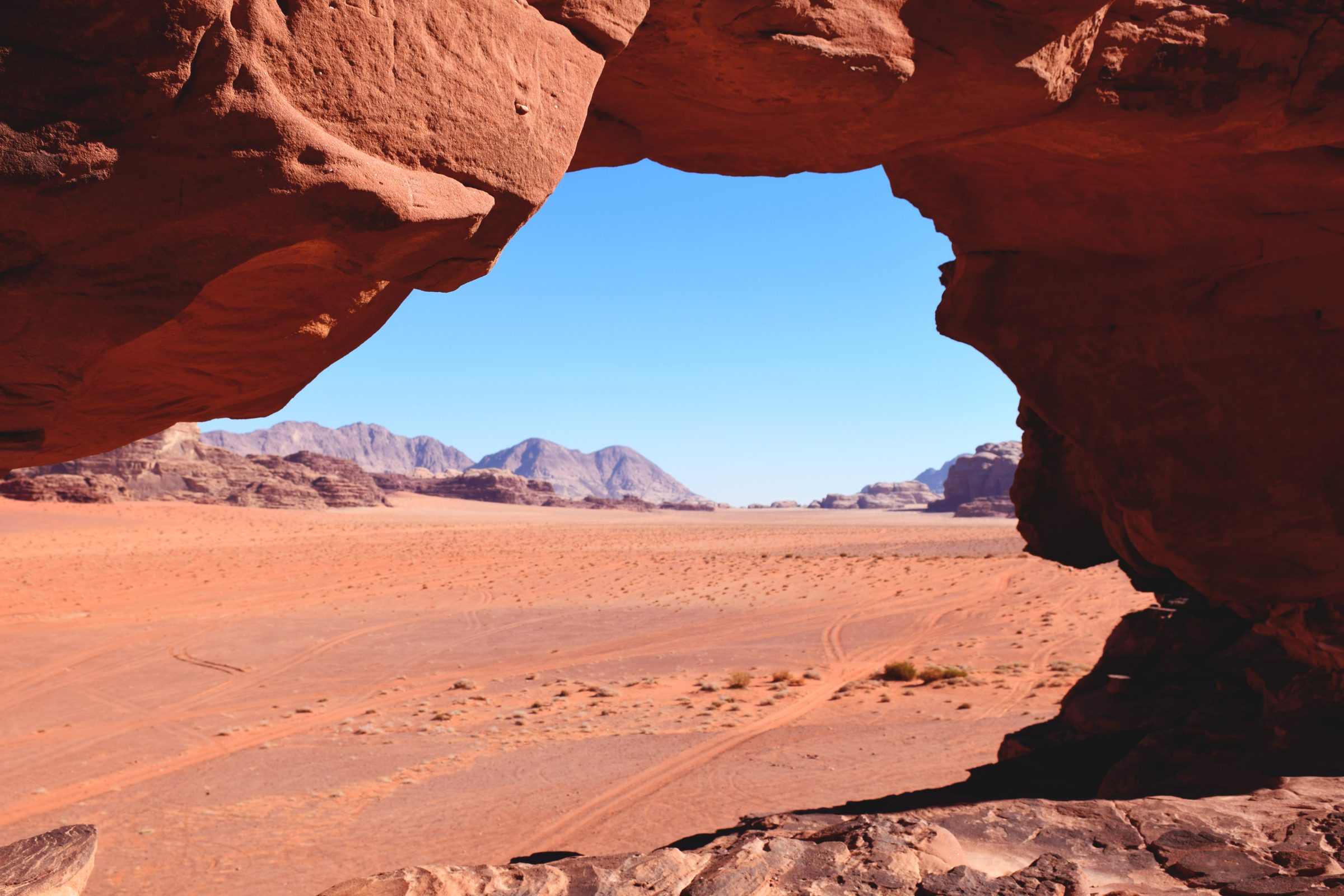 Un arco natural de roca enmarca las arenas rojas de Wadi Rum, Jordania