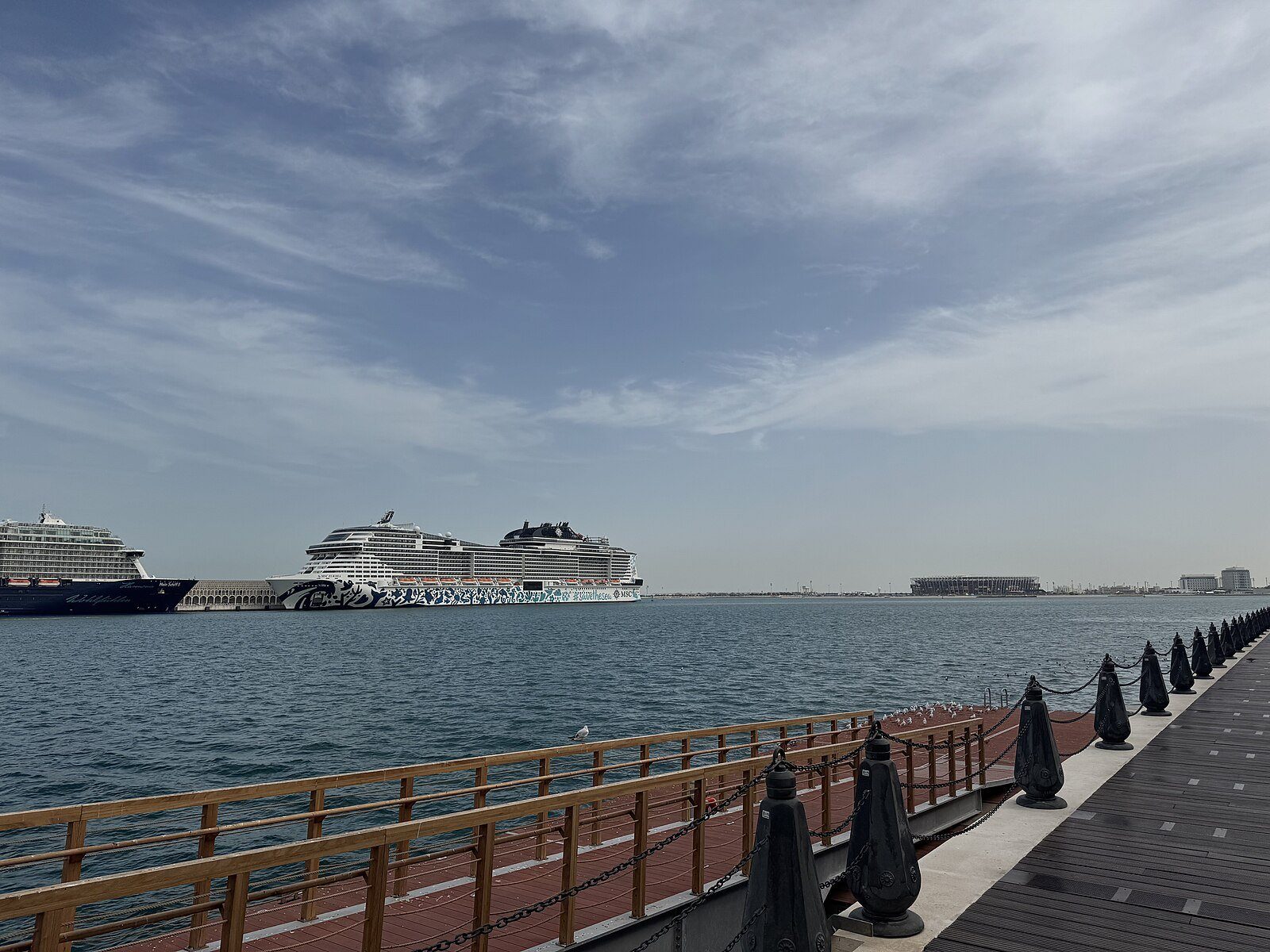 Cruceros atracados en el puerto de Doha, vistos a través de las tranquilas aguas de la bahía de Doha desde el paseo marítimo.